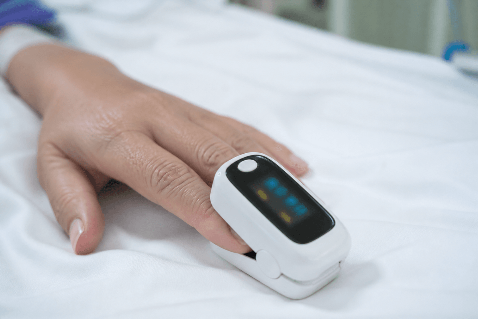 Pulse oximeter on a finger with display intentionally unreadable.
