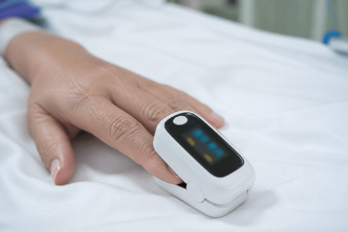 Pulse oximeter on a finger with display intentionally unreadable.