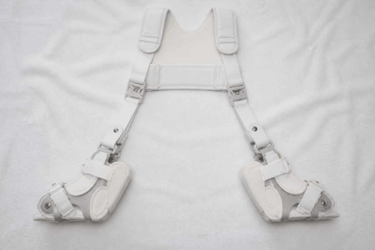 Pavlik harness laid flat on a white blanket without an infant.