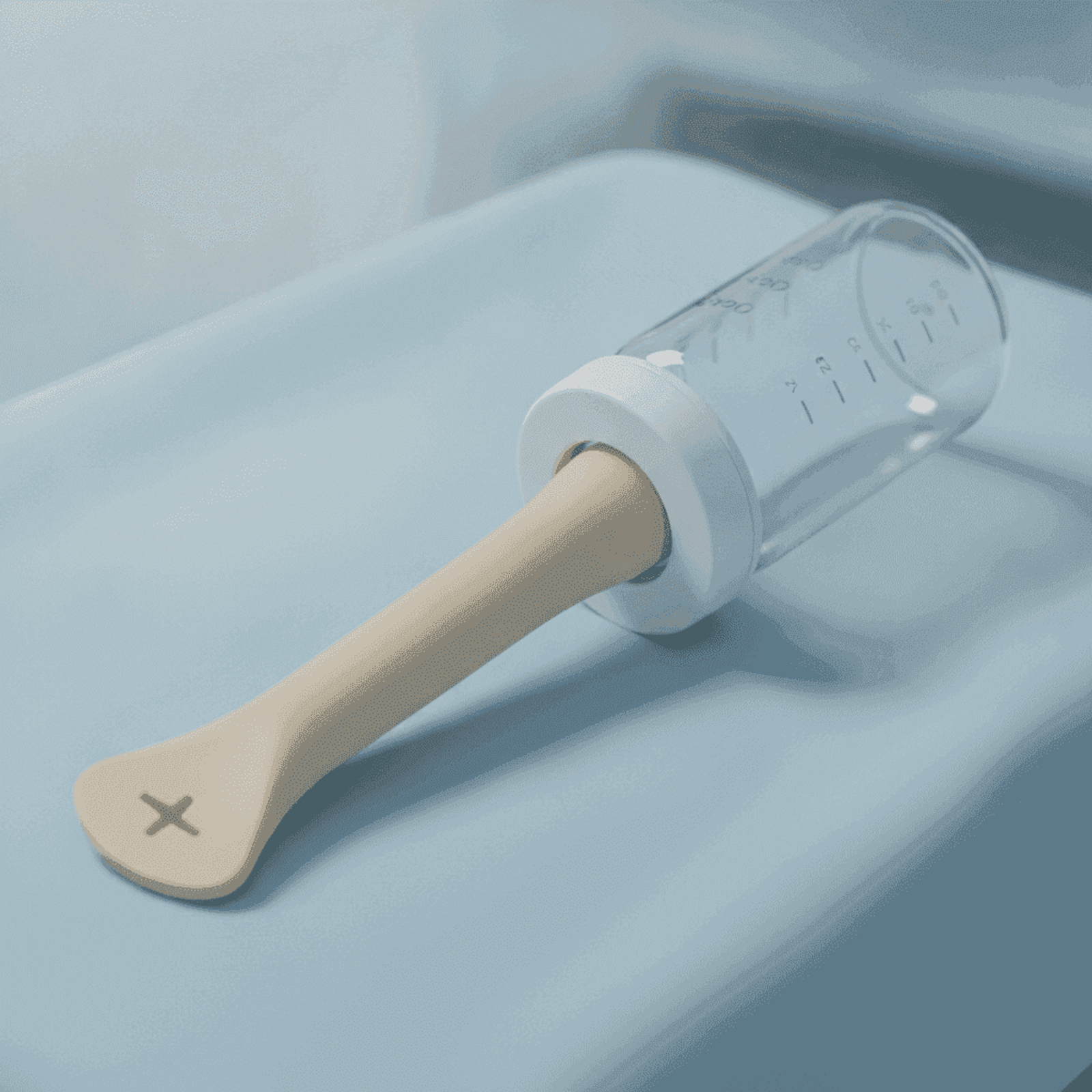 Specialized cleft-palate feeder bottle with soft elongated nipple on white linen.