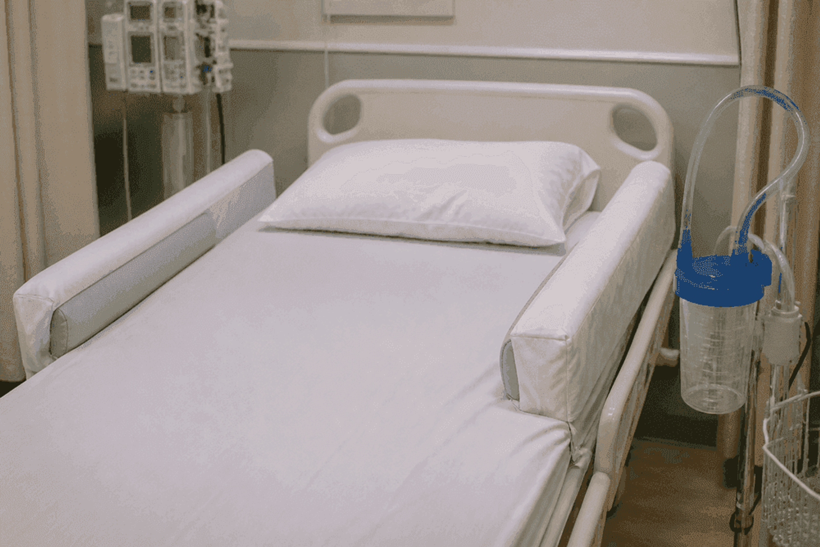 Padded side rails and suction staged at an empty hospital bedside.