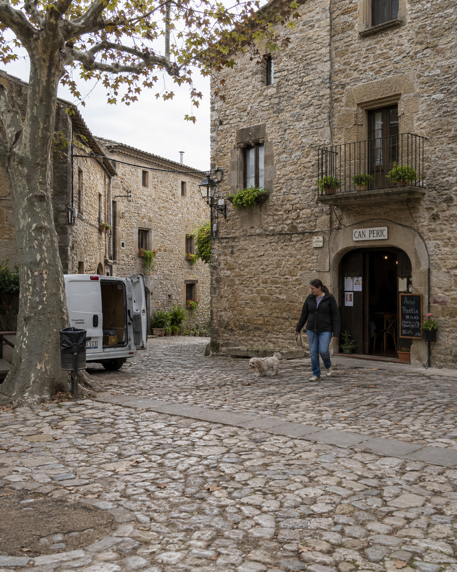 A street in Peratallada, in the inland Baix Empordà, on a weekday morning, with a resident walking past the dry-stone façades.