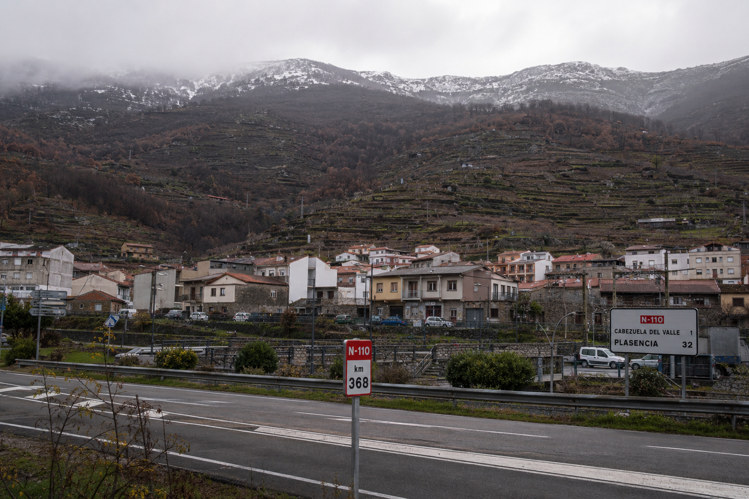 Cabezuela del Valle on the N-110 in the Valle del Jerte, seen in autumn with the worked cherry terraces rising behind the town and the high Tormantos cumbres above.