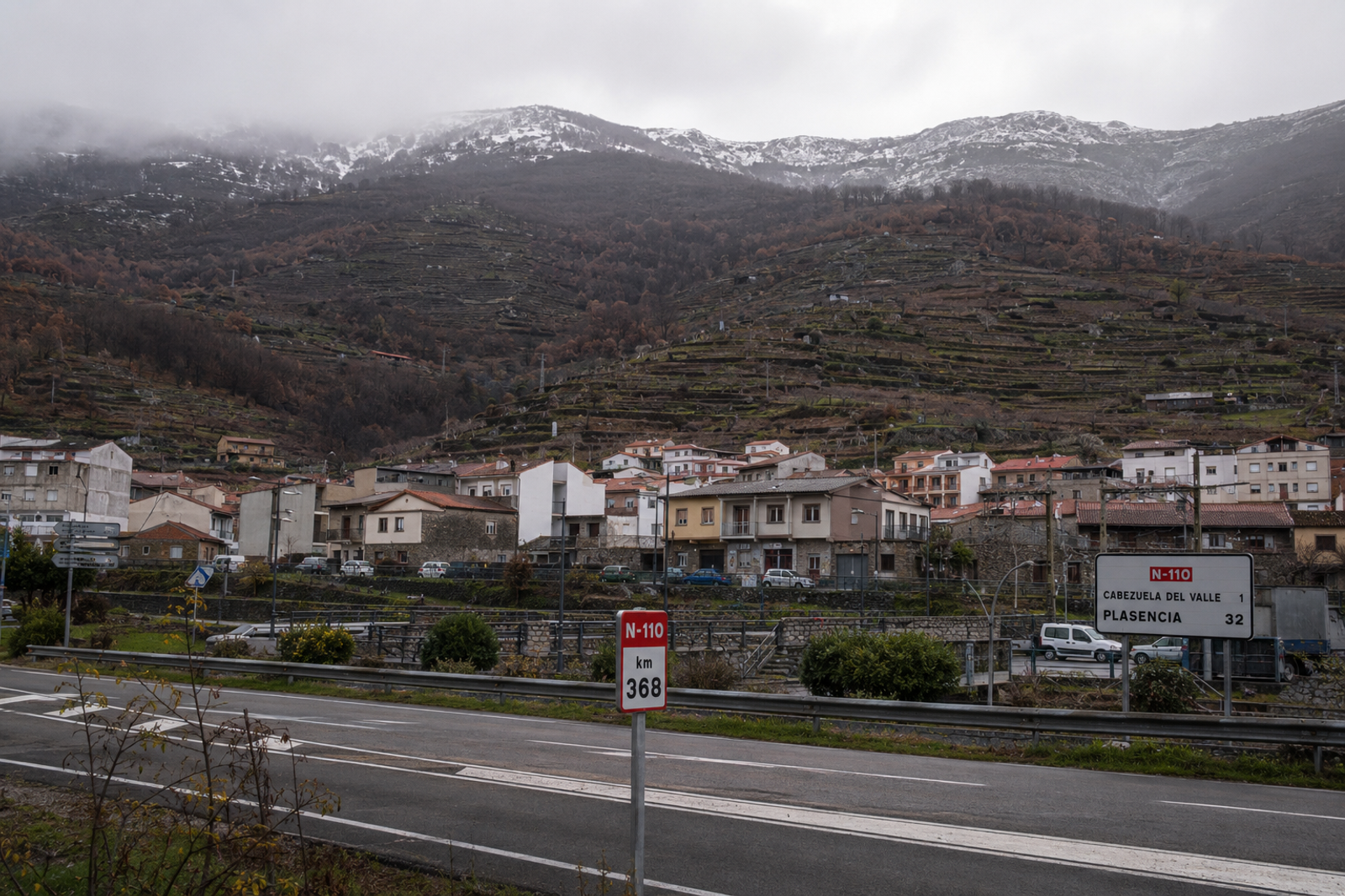 Cabezuela del Valle on the N-110 in the Valle del Jerte, seen in autumn with the worked cherry terraces rising behind the town and the high Tormantos cumbres above.