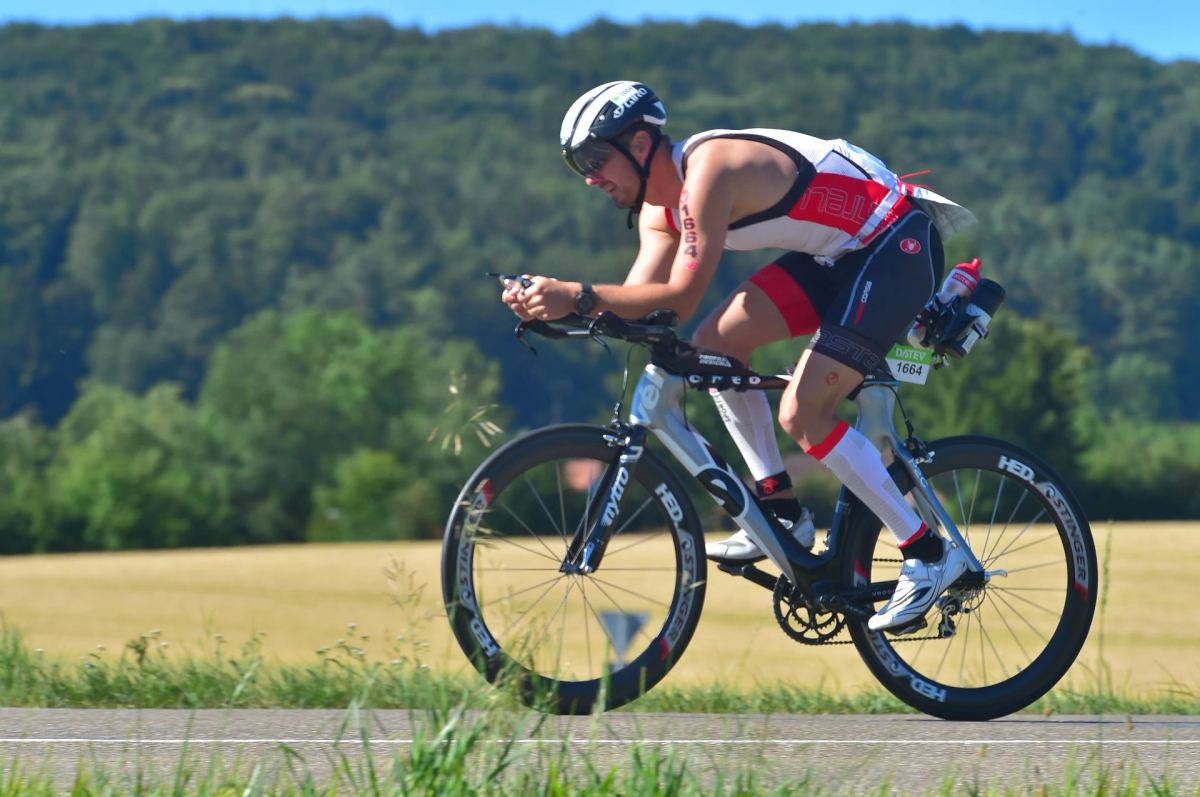 Triathlete riding a time-trial bike on aero bars during a race
