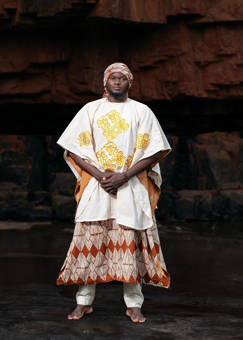 Marie Kaba – Haute couture en bogolan malien. Une création masculine qui associe broderies dorées, étoffes aux motifs géométriques et savoir-faire textile traditionnel, célébrant le patrimoine culturel du Mali à travers une vision contemporaine de la mode africaine.