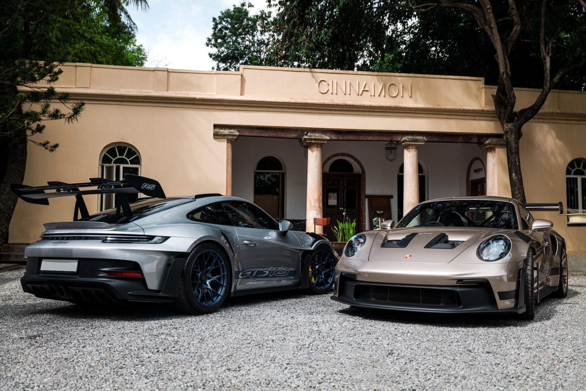 Two Porsche 911 GT3 RS parked on gravel in front of a colonnaded building