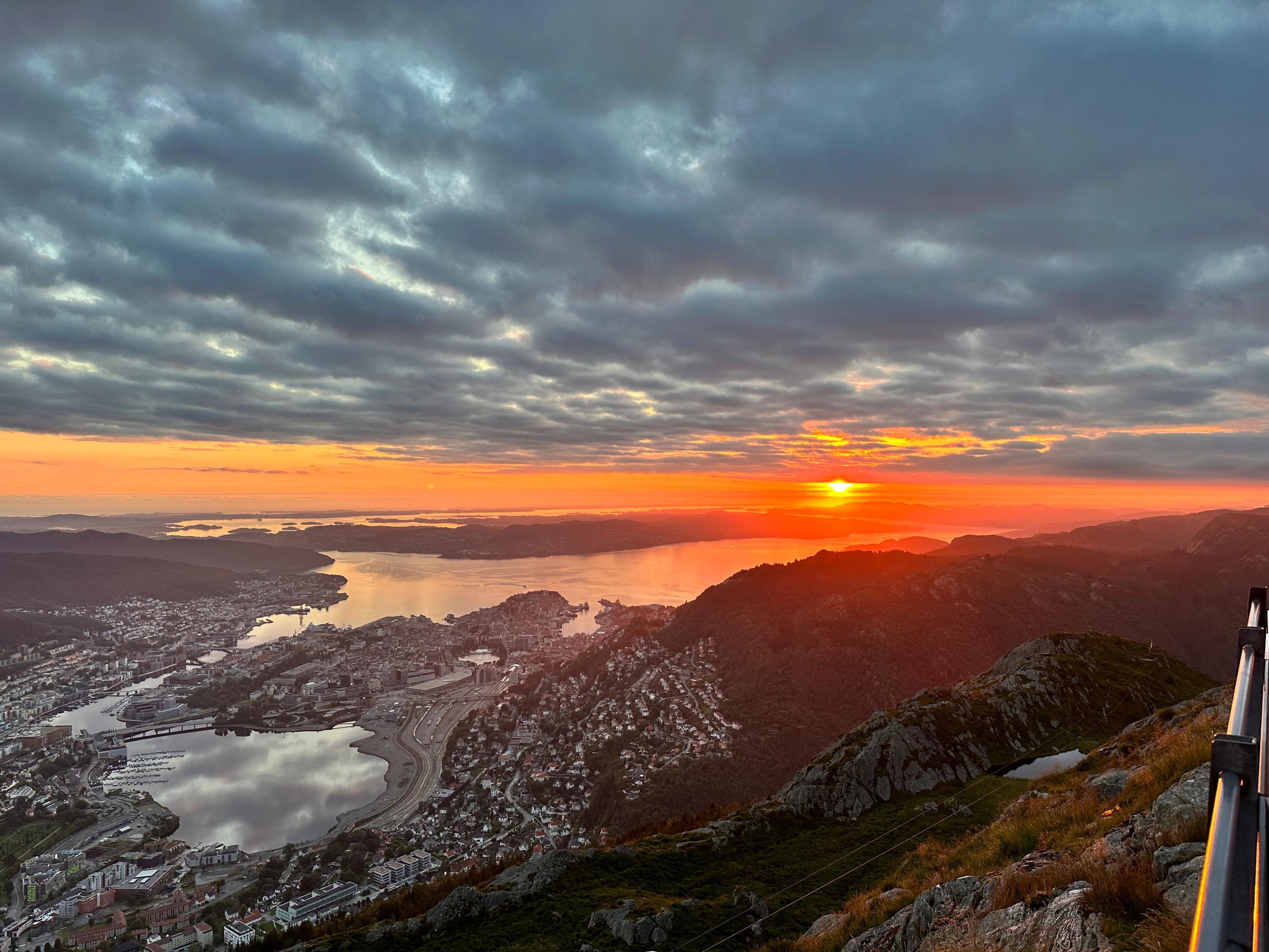 Solnedgang sett fra Ulriken, med byen i skygge under et tungt skydekke.