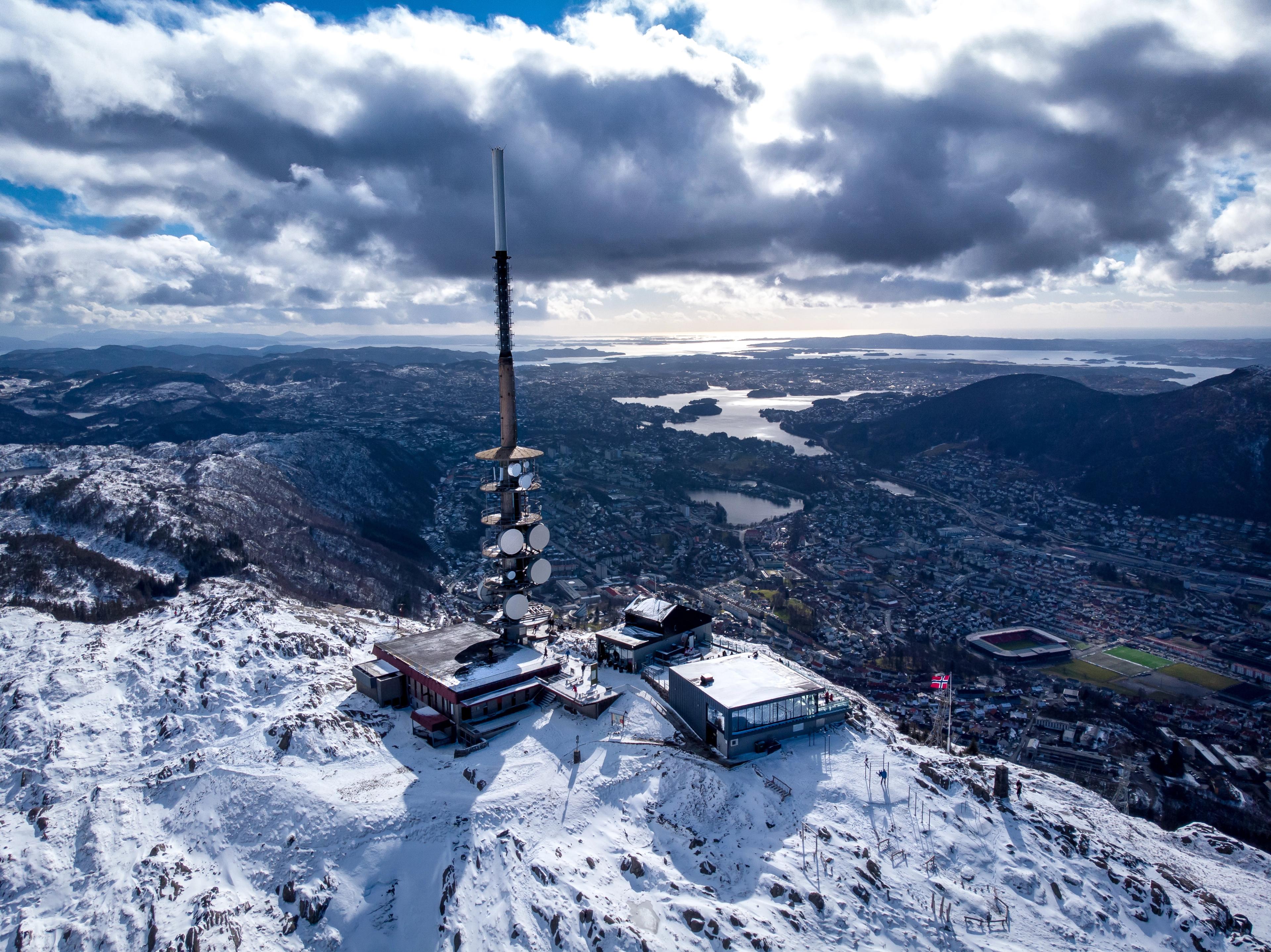 Masta på Ulriken dekket av rim og snø, med byen og fjellene rundt i bakgrunnen.