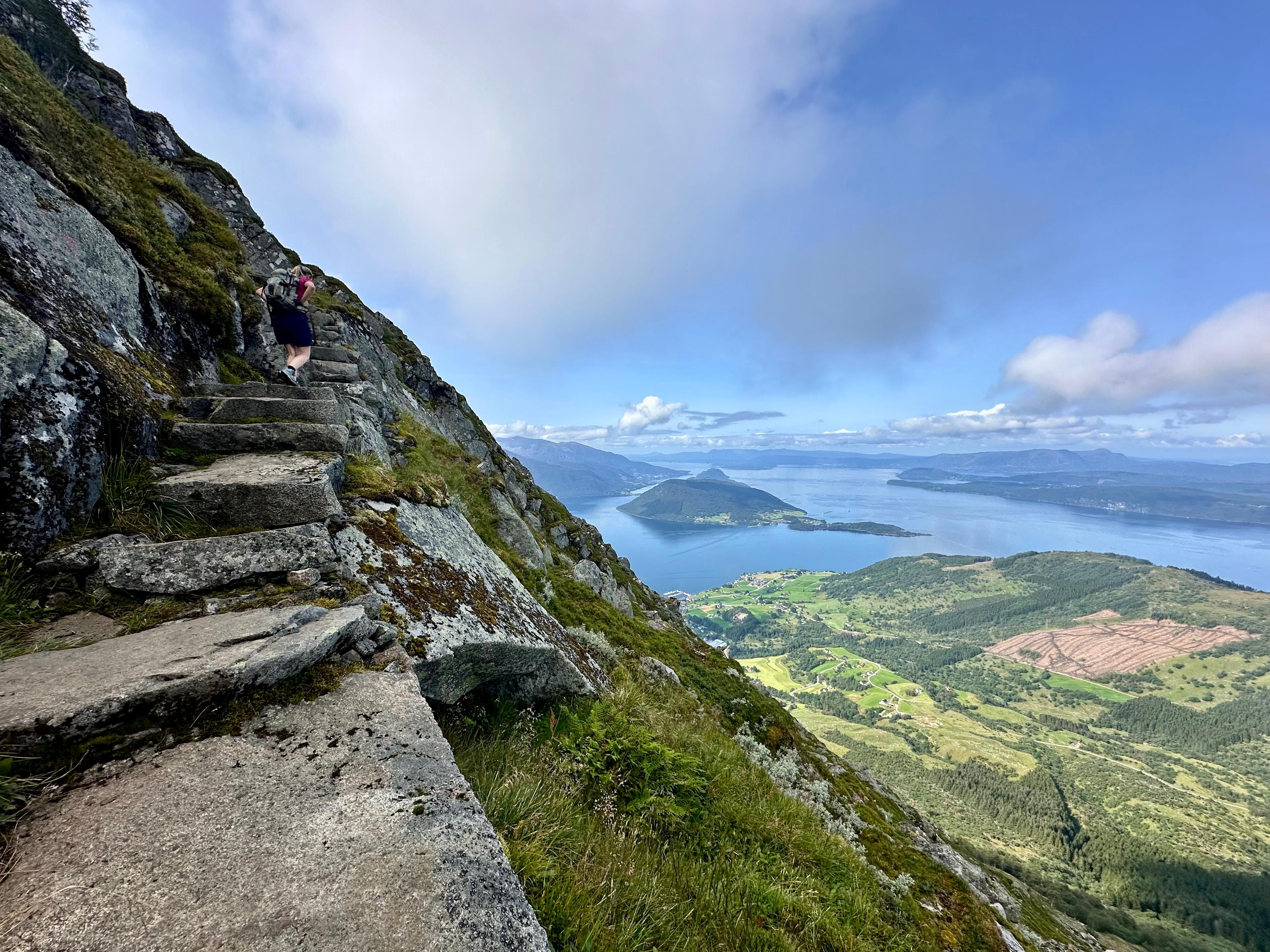 Steinlagte sherpatrapper i bratt fjellside med fjorden under
