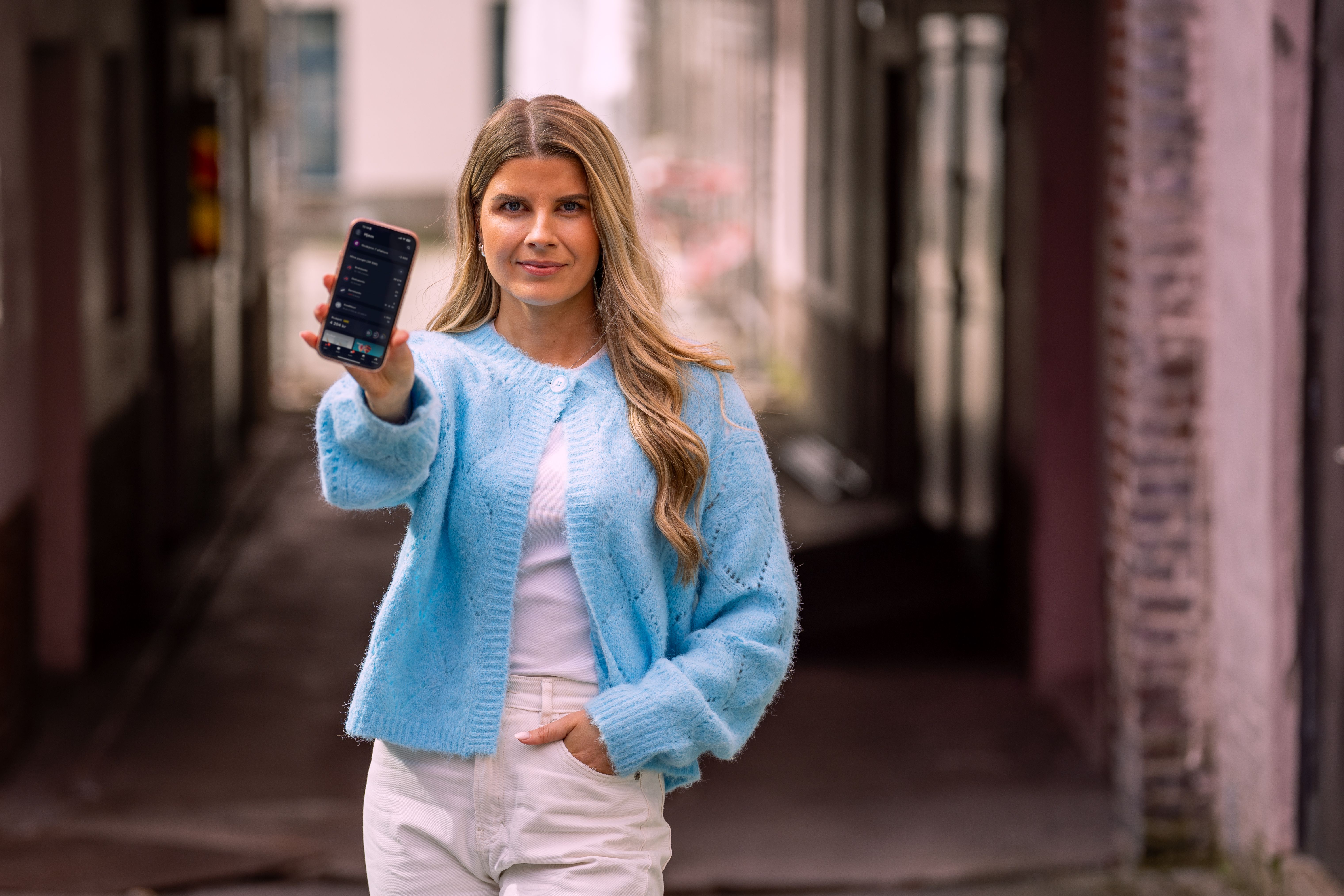 Ung kvinne som viser frem mobilen med Bulder-appen