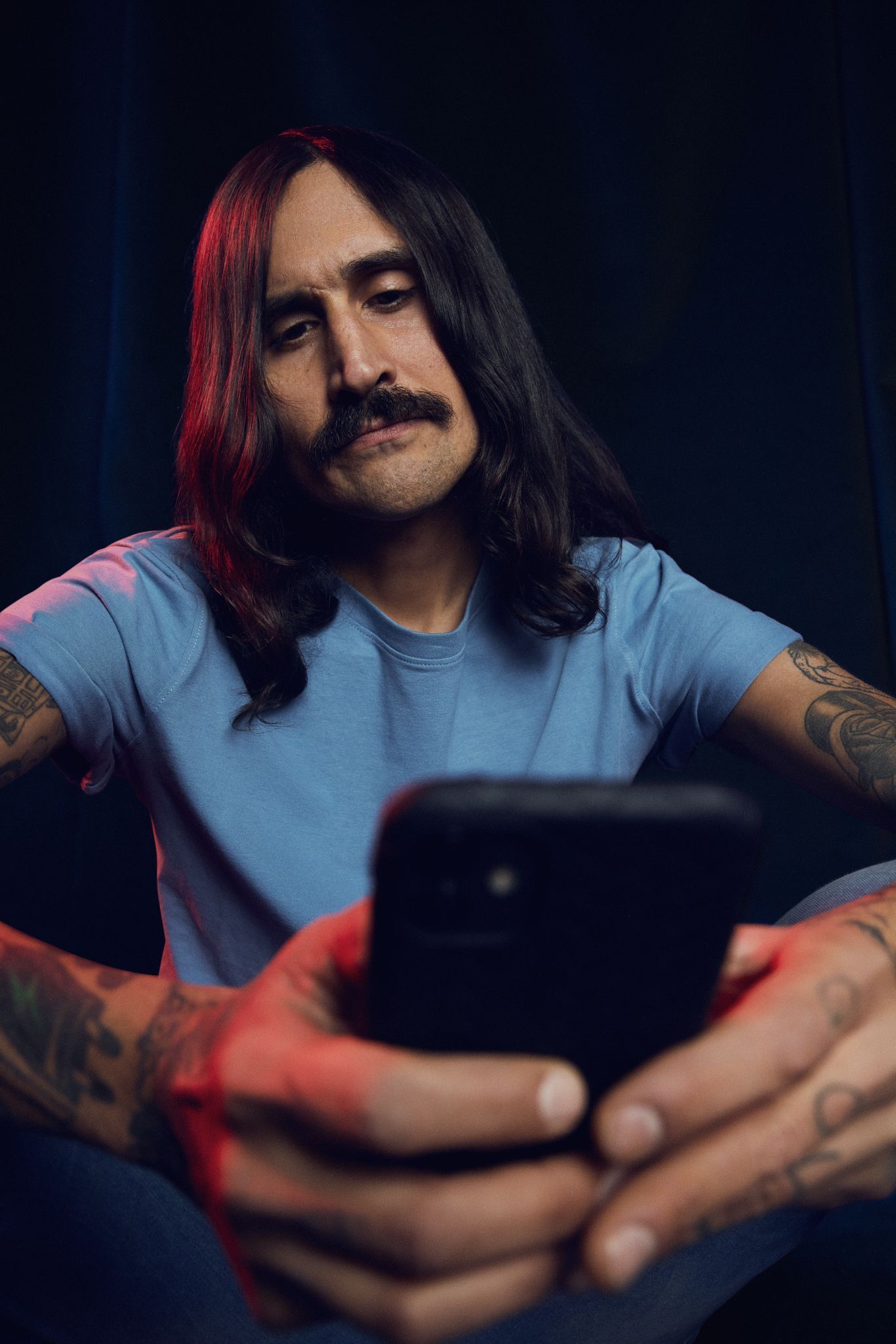 Bilde av mann med langt svart hår og bart som holder mobiltelefon i hånden og søker rammelån