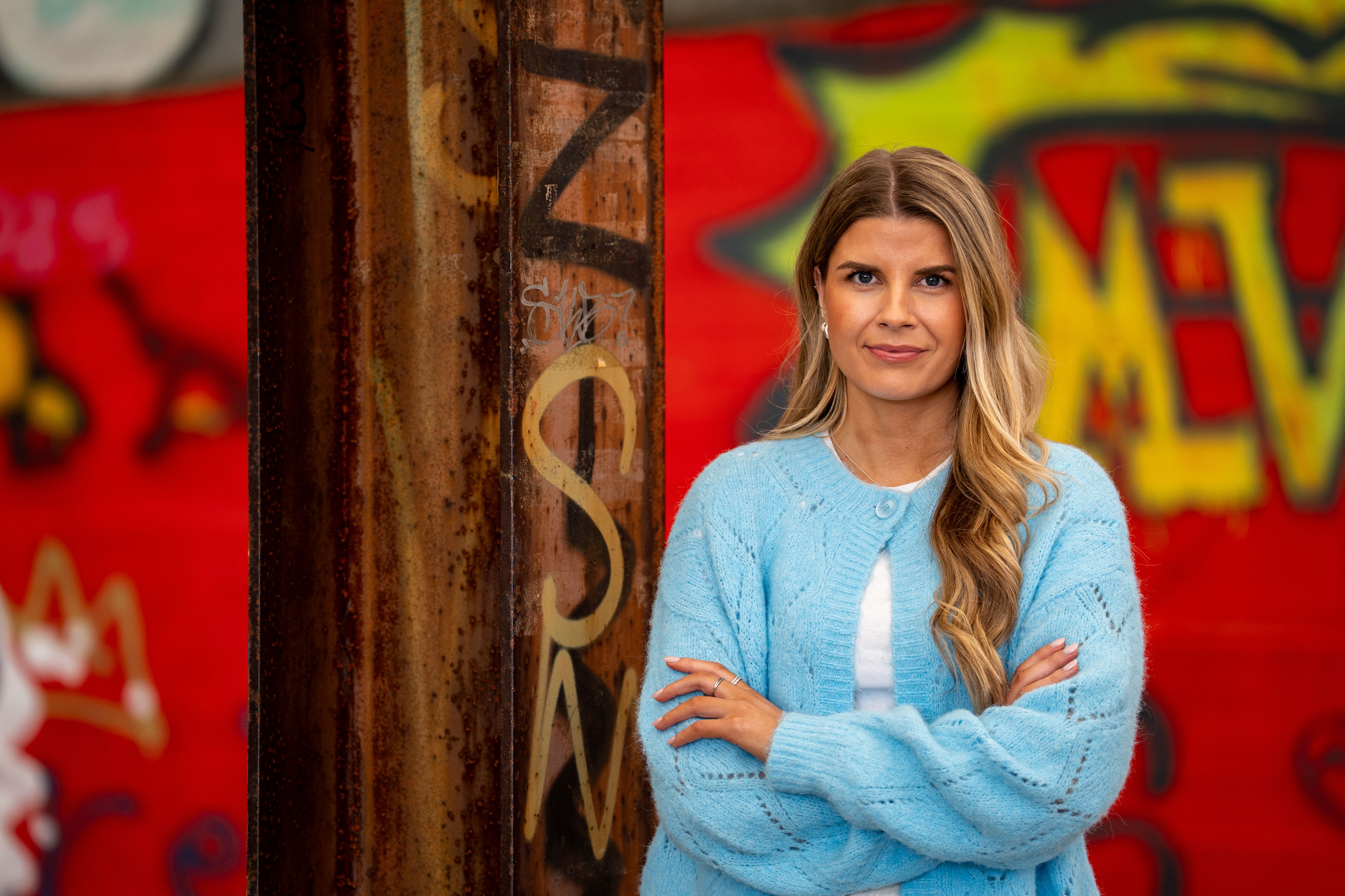 Bilde av kul dame fra Bulder som står med armene i kryss foran en grafittivegg.