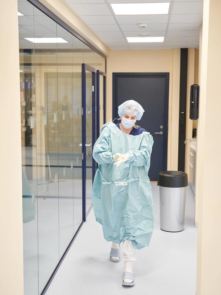 Veterinær i steril operasjonsdrakt forbereder seg til kirurgi på dyreklinikk. Moderne fasiliteter og strenge hygienerutiner sikrer trygg behandling for dyr.