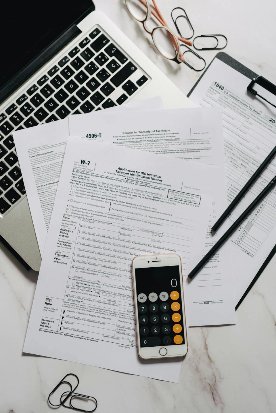 Tax preparation forms with calculator and laptop