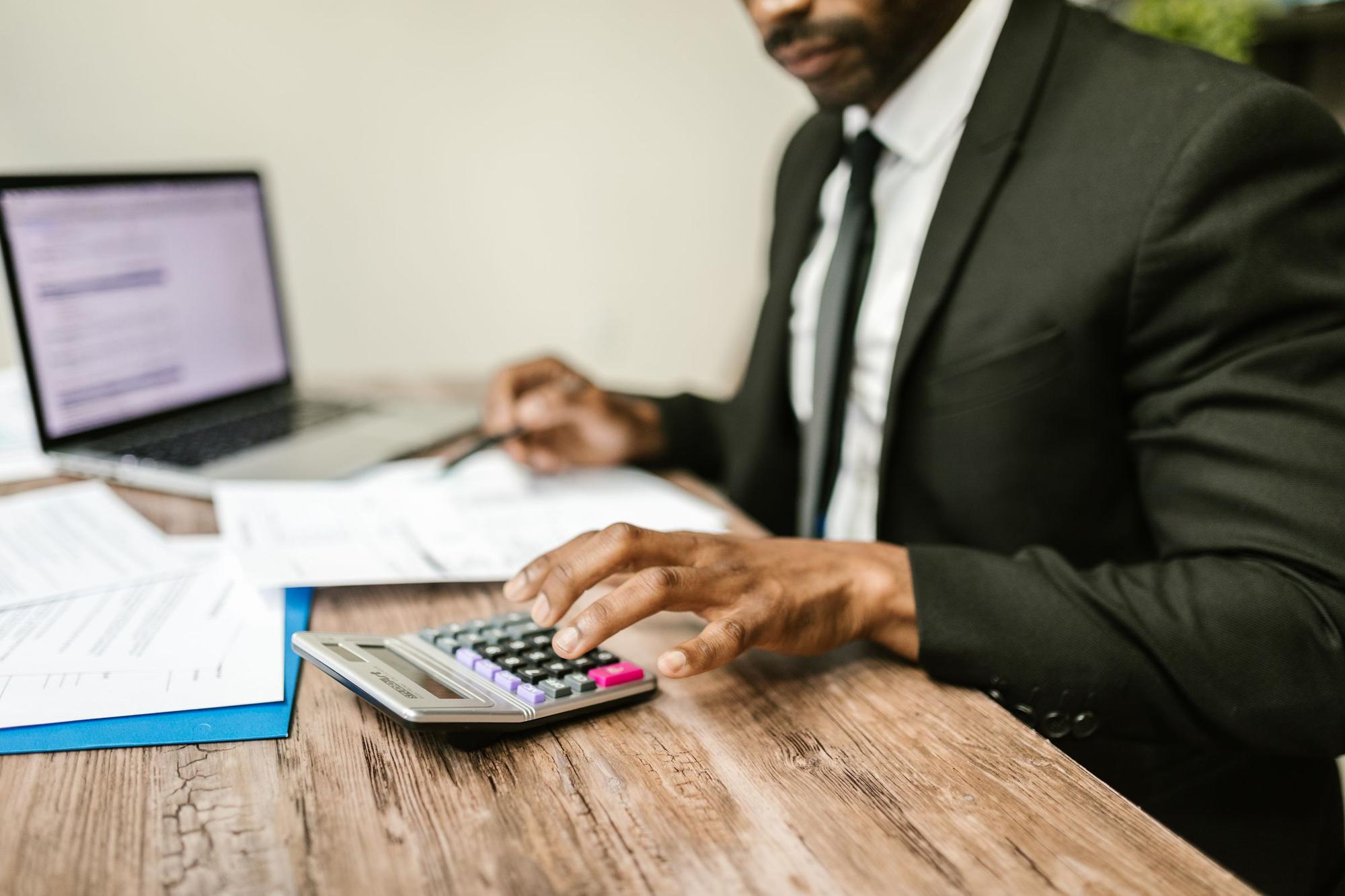 Black accountant reviewing tax documents with a calculator