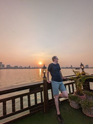 Lucas Silbernagel standing on a riverboat at sunset in Phnom Penh, Cambodia
