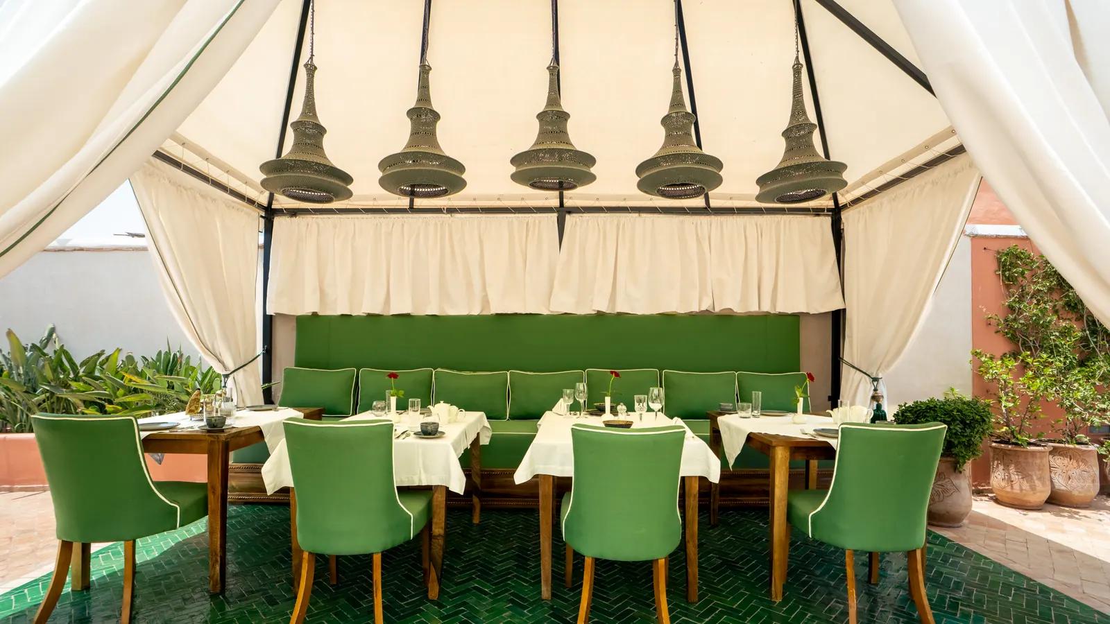 Covered dining space with a green banquette