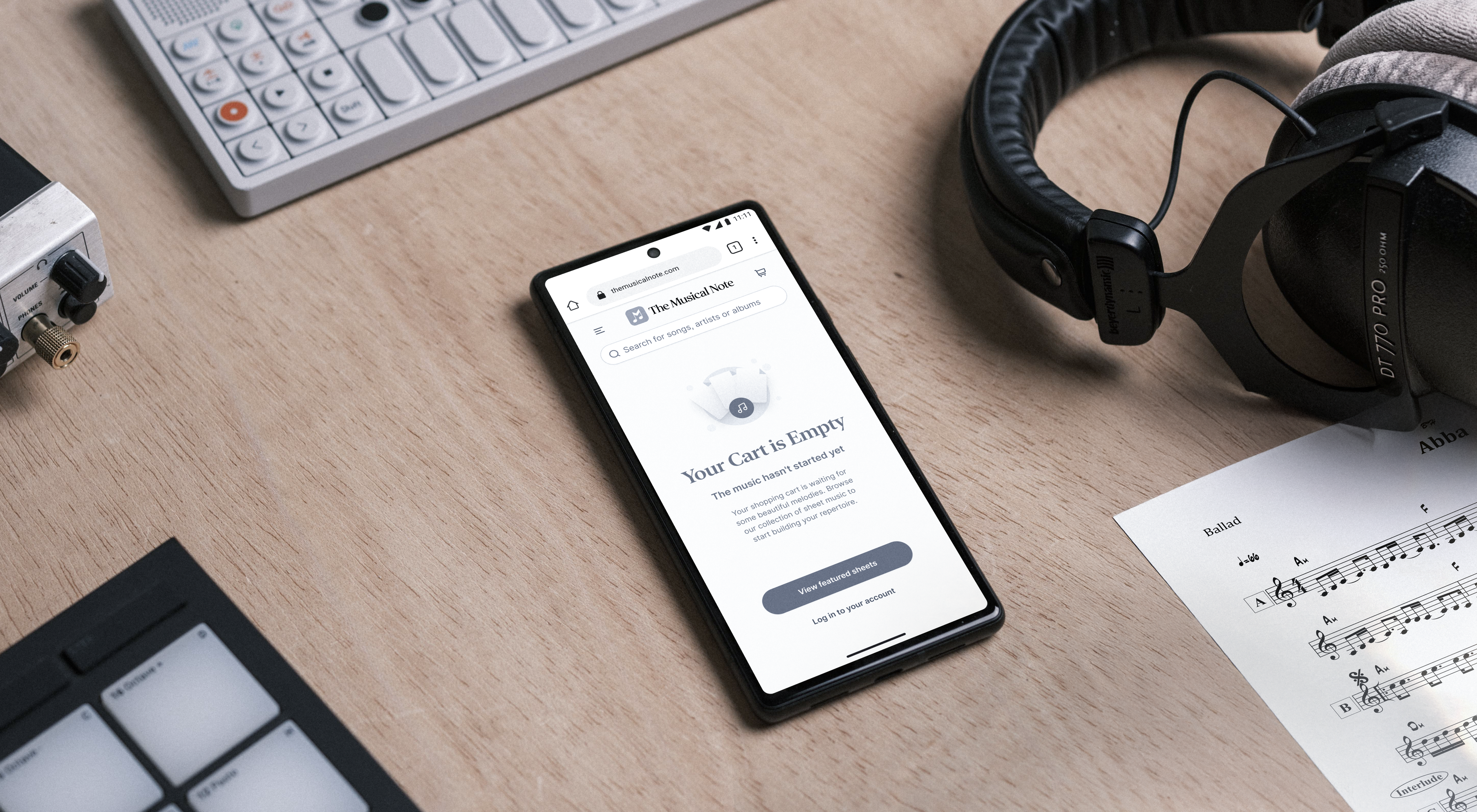 The Musical Note: Mobile store interface on a phone beside headphones.