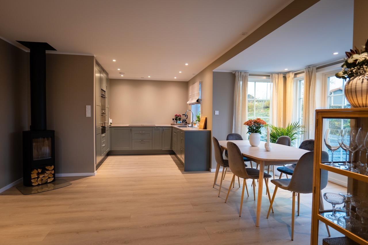 Åpen stue- og kjøkkenløsning med moderne farger og lekker peisovn