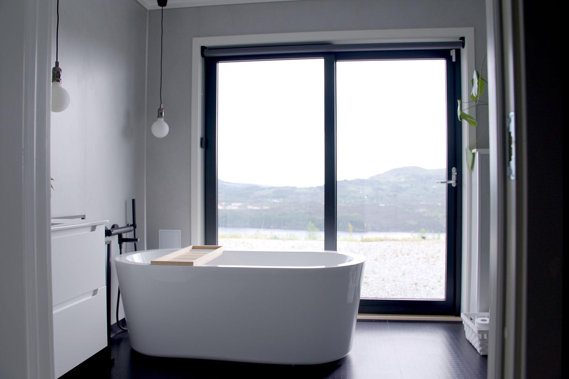 Badekar rett ved store skyvedører ut mot hagen