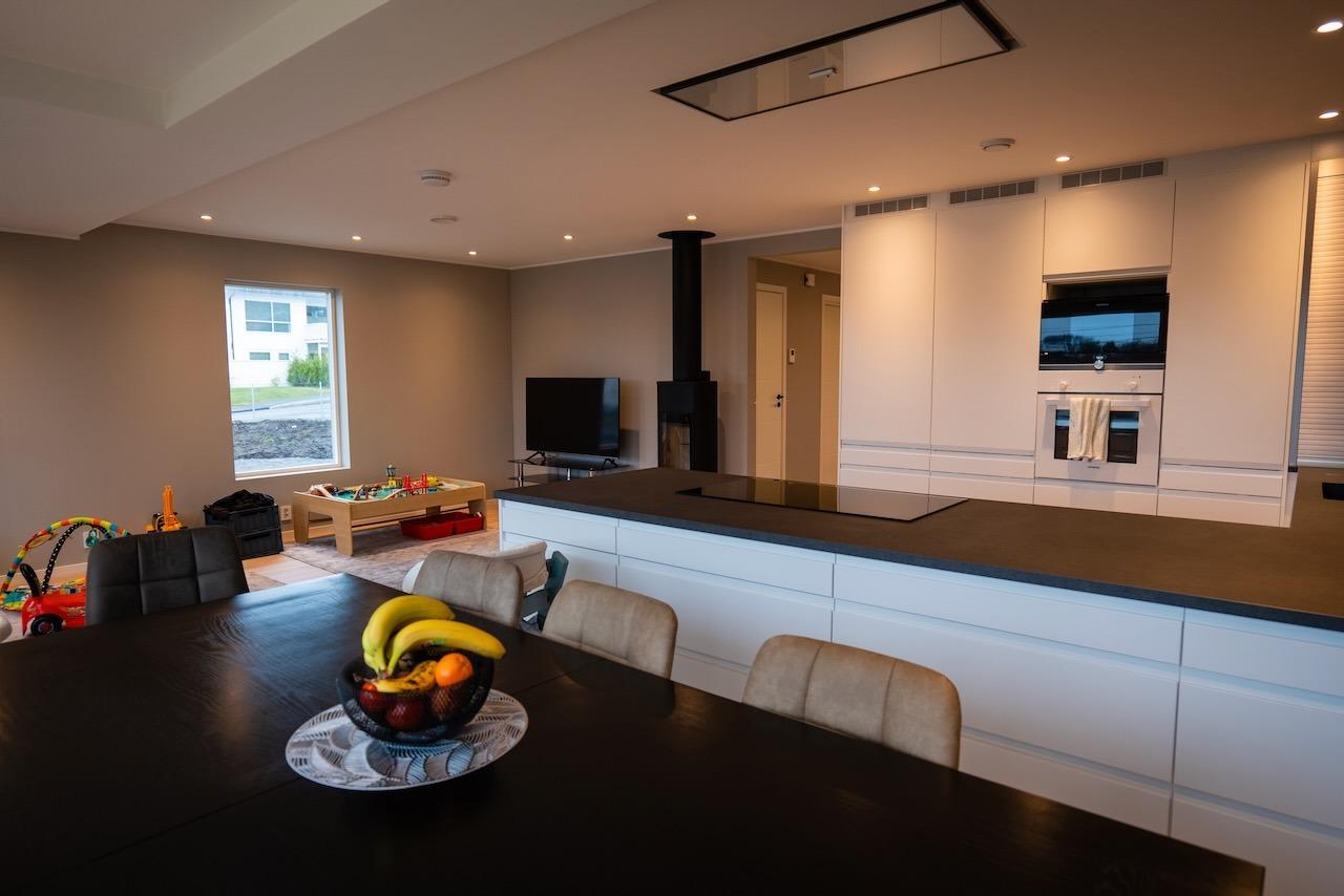 Åpen stue- og kjøkkenløsning med moderne farger og lekker peisovn