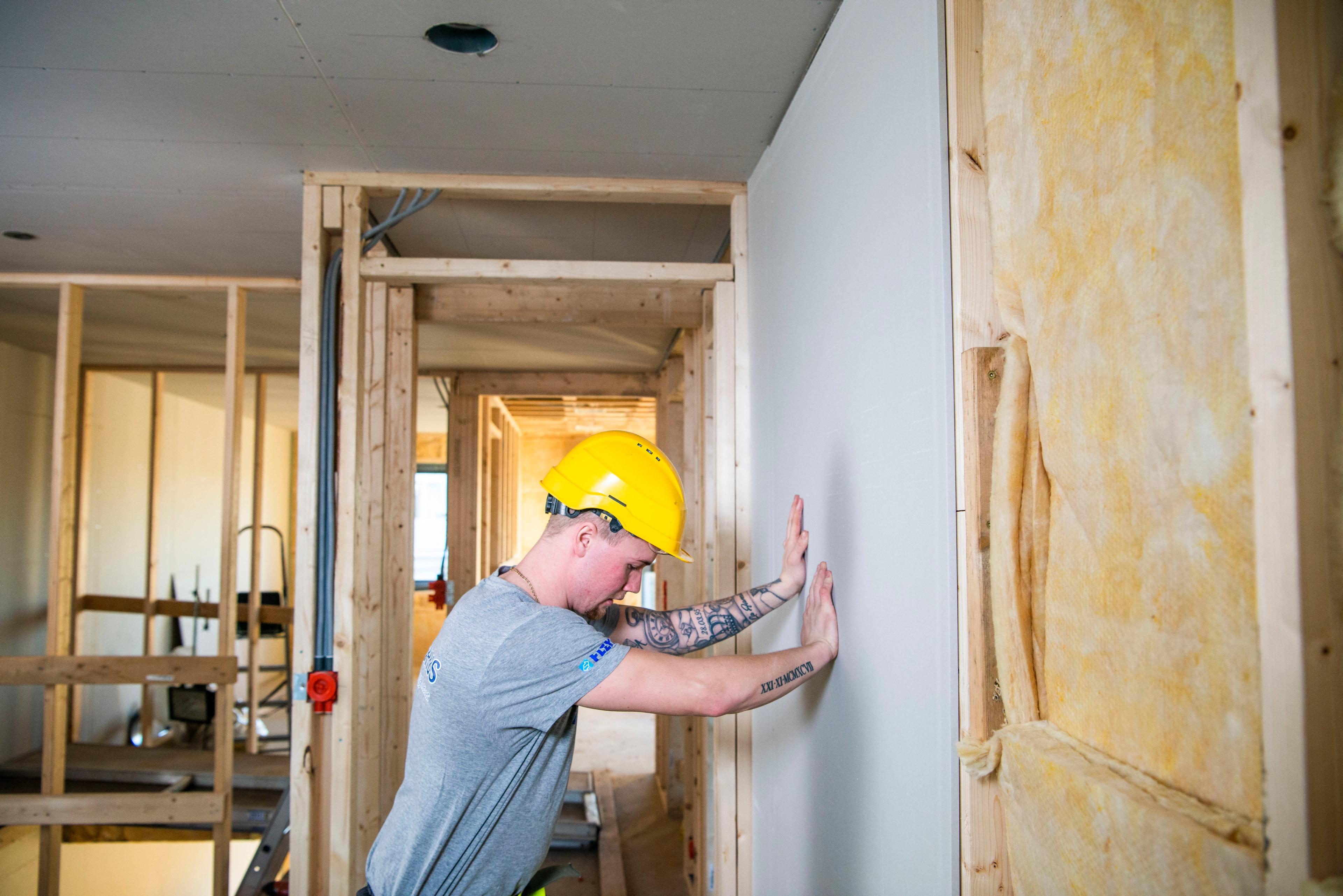 Tømrer som setter på plass vegger med isolasjon i veggen