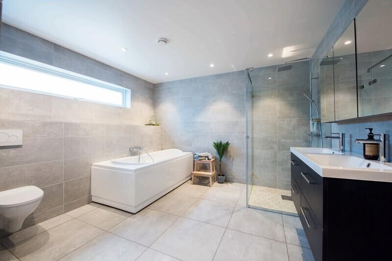 Hovedbadet er stilrent og enkelt med store fliser i varme gråtoner