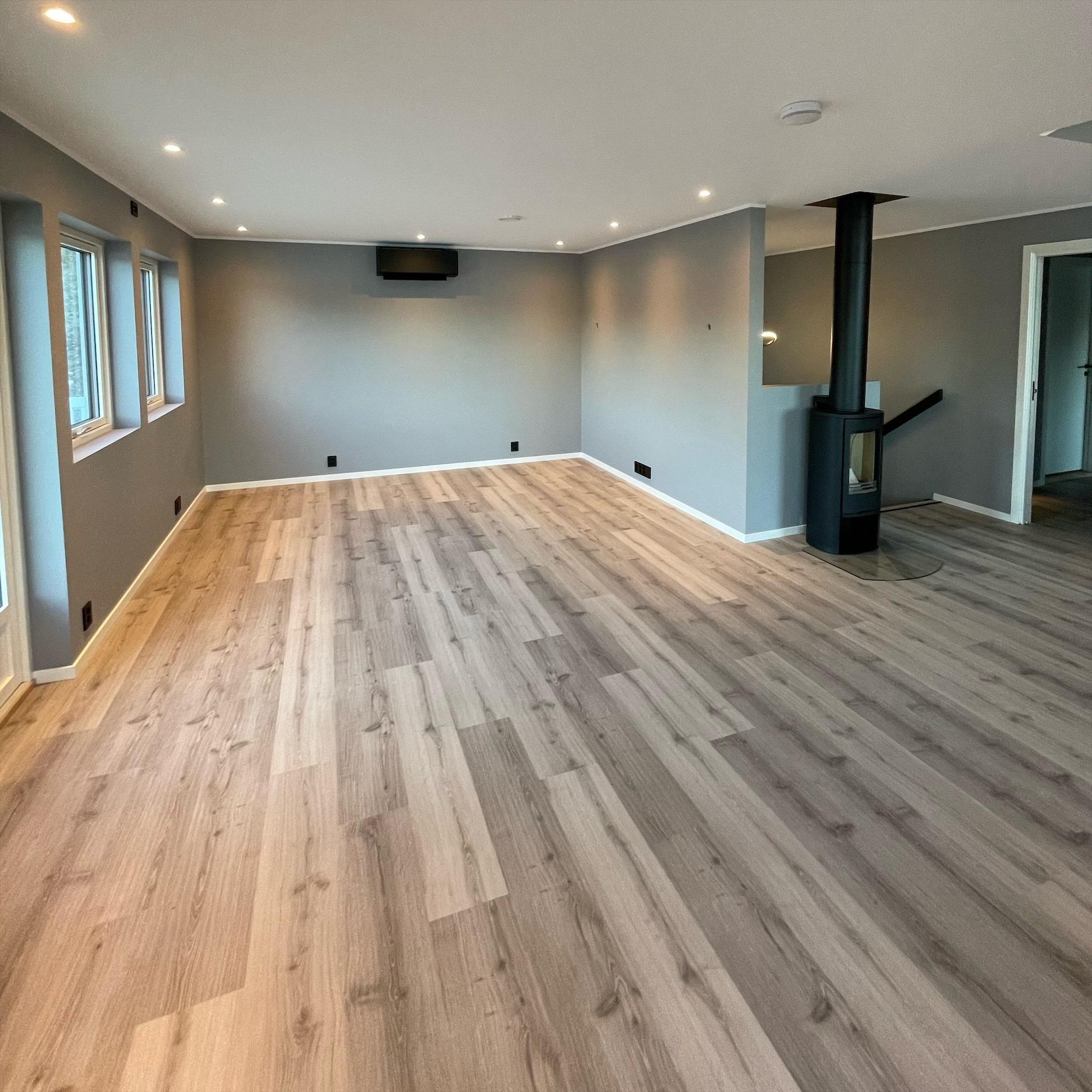 STUE 2.ETASJE: Sorte detaljer, spotter i taket og sort ildsted levert fra Varmefag. Her ser man en stor flate med venylgulv som kunden har valgt.