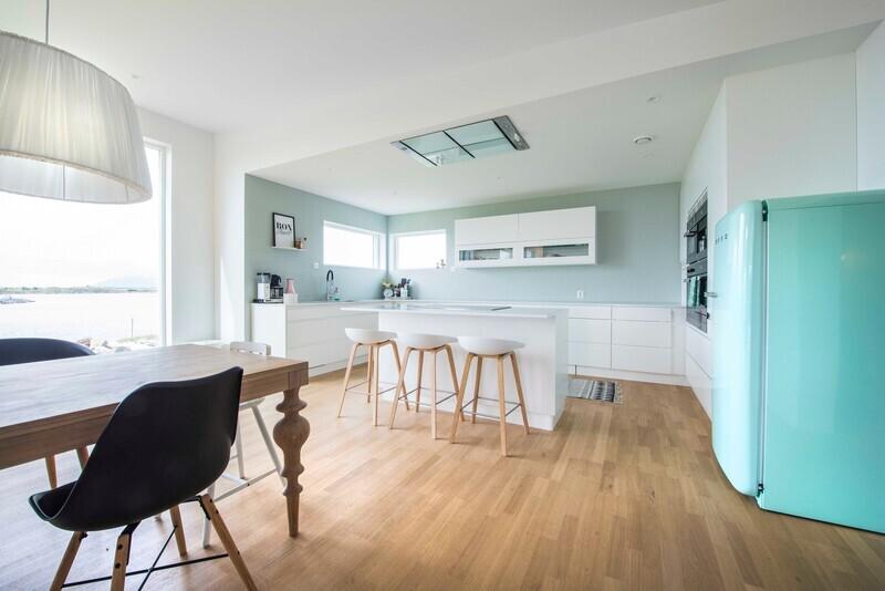 Hvitt og turkis går igjen på det moderne, åpne kjøkkenet. Det lyse eikegulvet gir varme til rommet