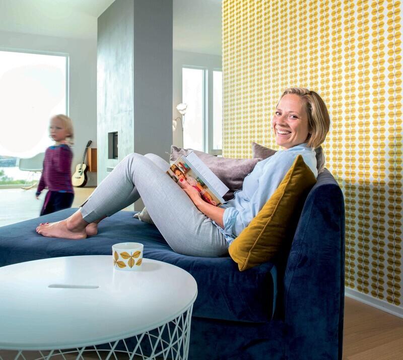 Cathrine sitter i sofaen og leser