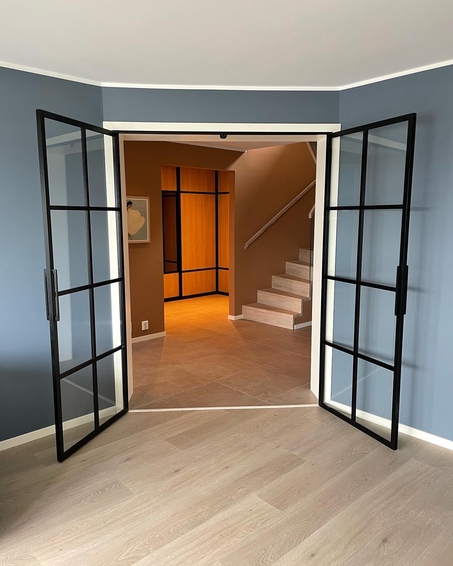 Tidligere kjellerleilighet med sorte doble dører med glass