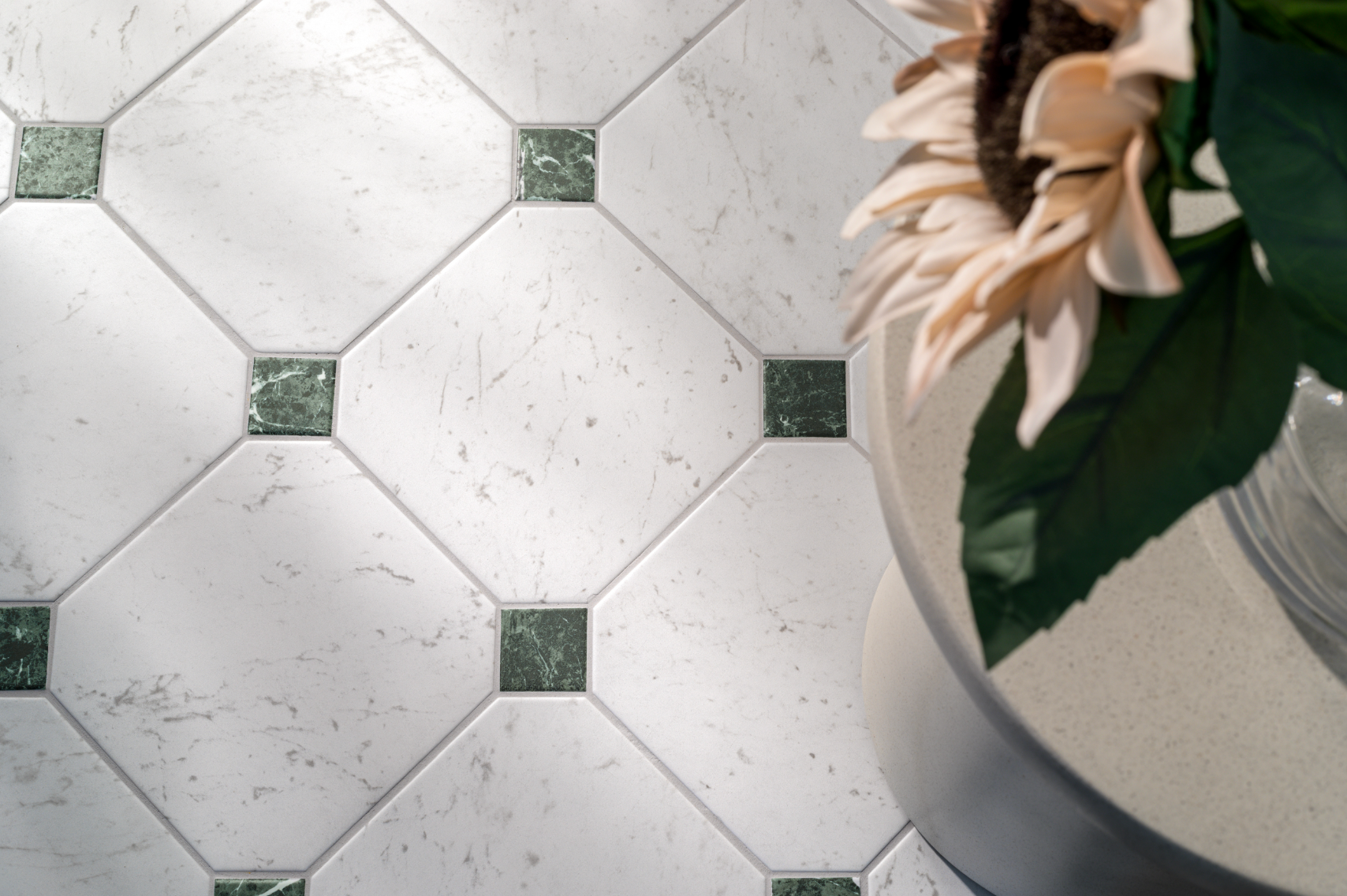 Diagonal white marble tiles with dark green square accents, next to a flower in a vase.