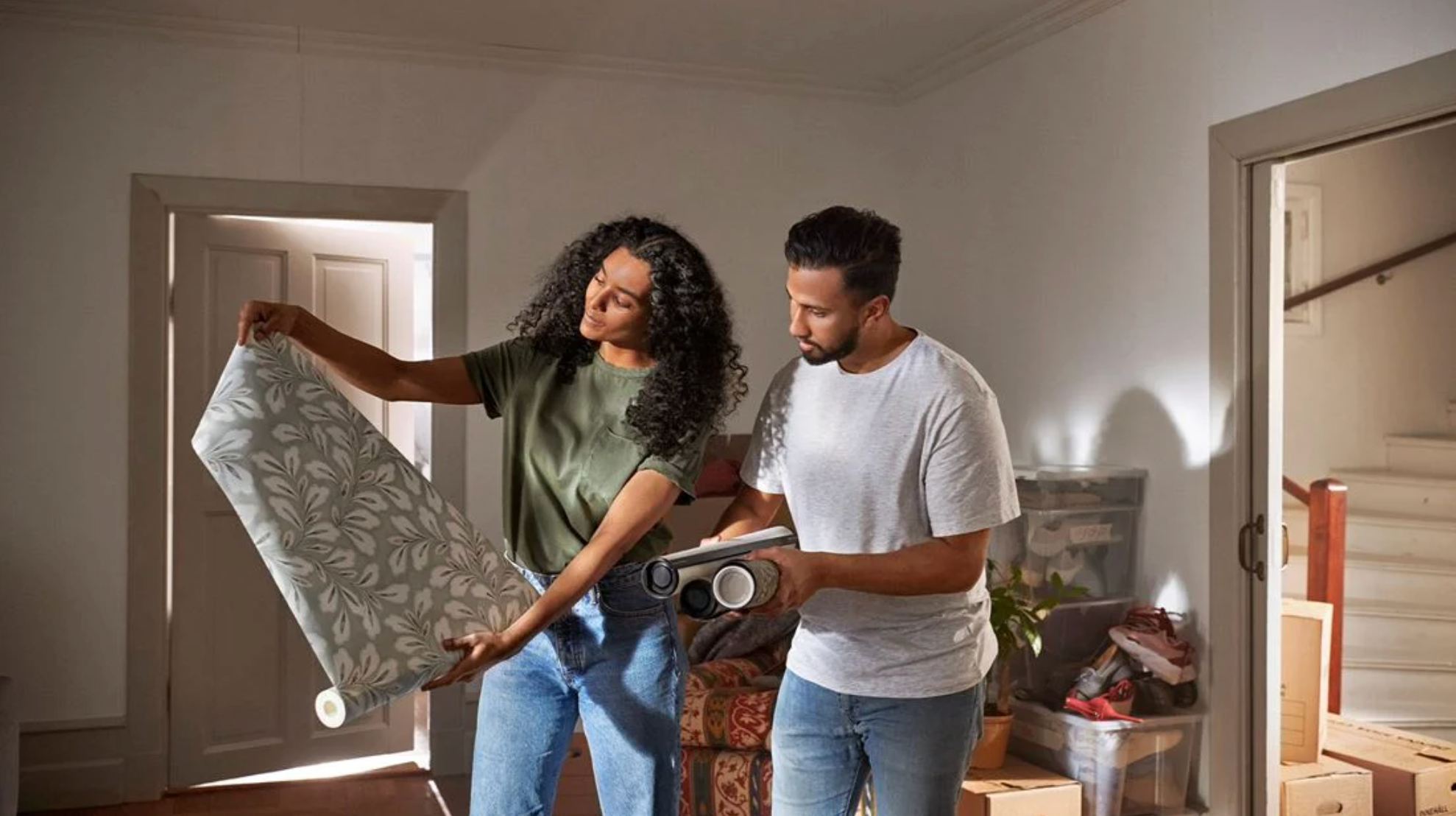 A couple choosing wallpaper in a room with moving boxes.