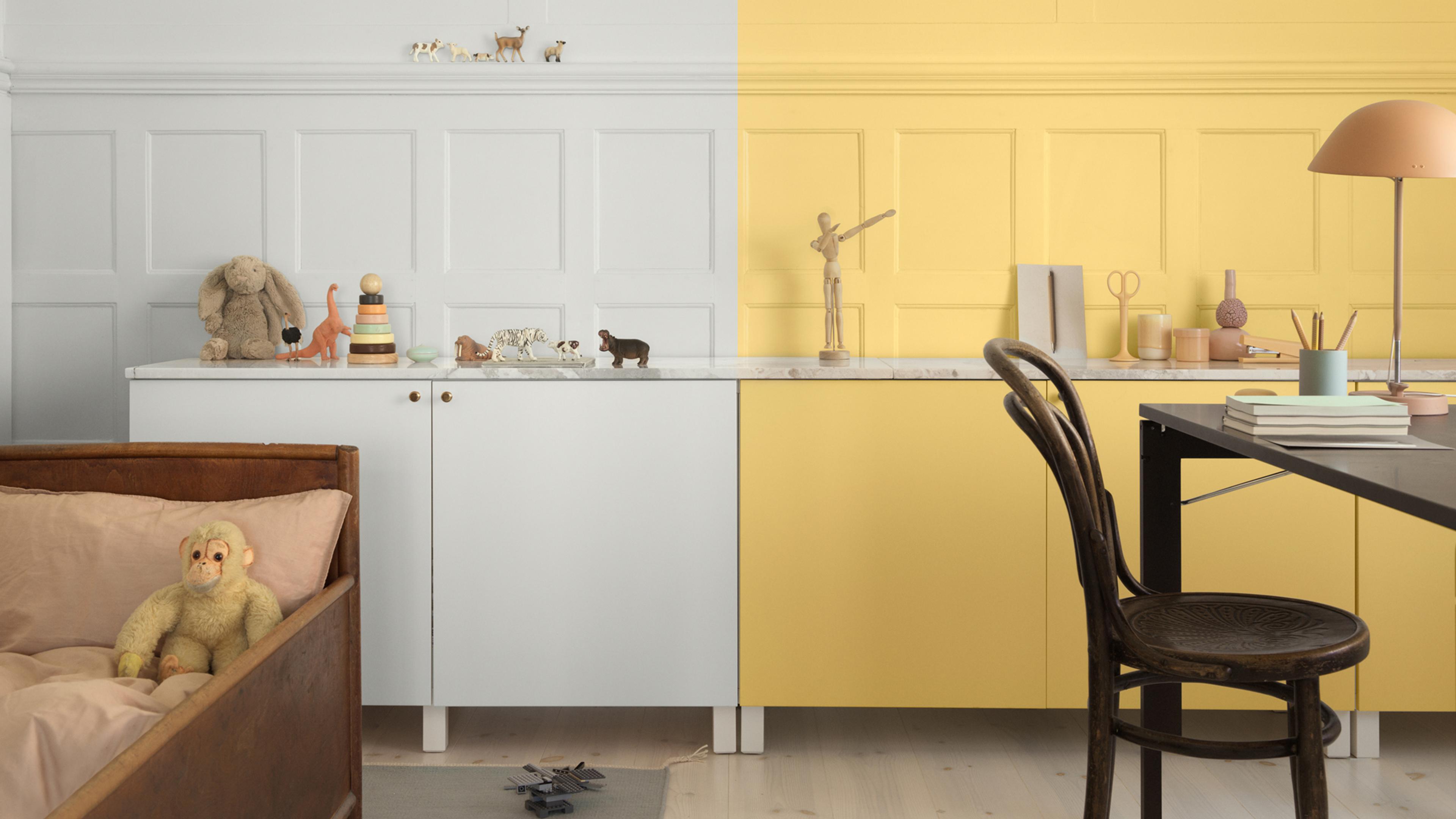 A room split in half: one side white with a child's bed and toys, the other side yellow with a desk and chair.
