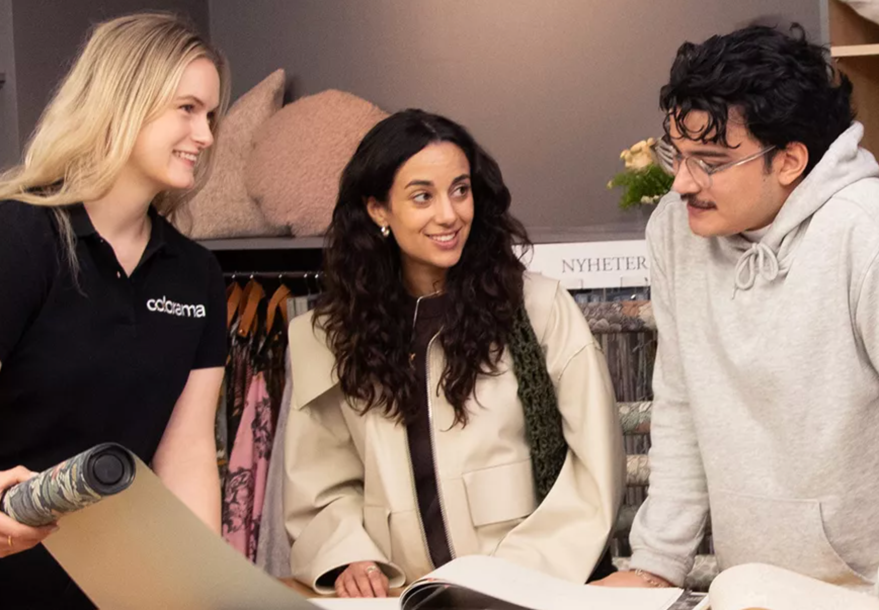 An Oddrama employee shows design samples to two customers.