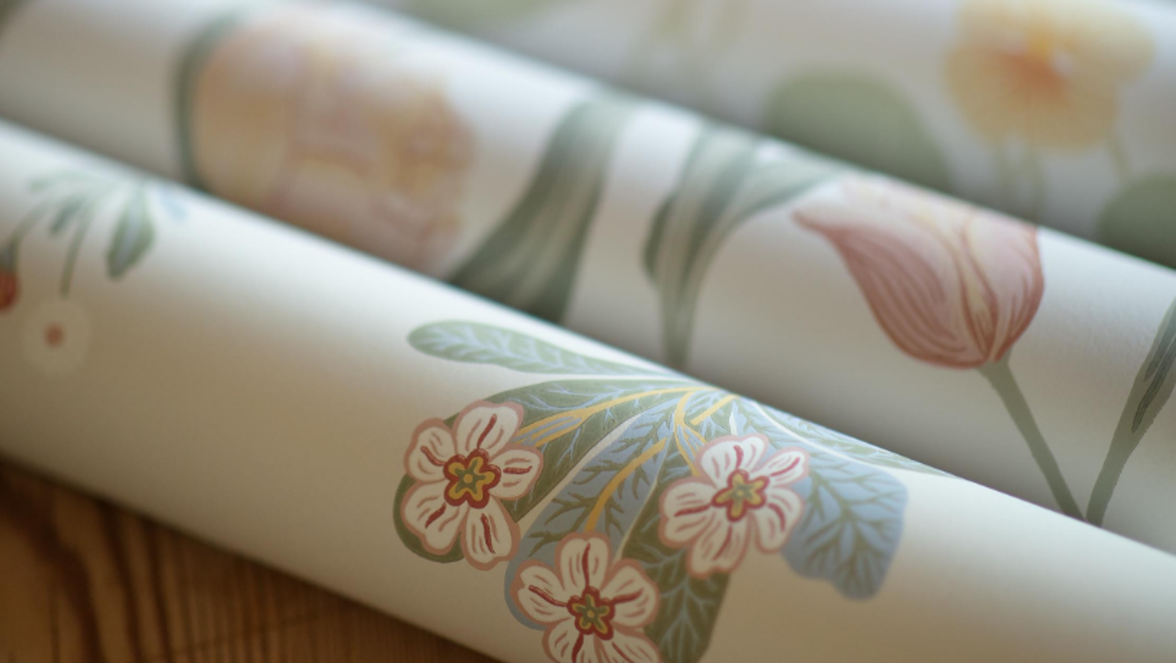 Rolls of wallpaper with a delicate pastel floral pattern.