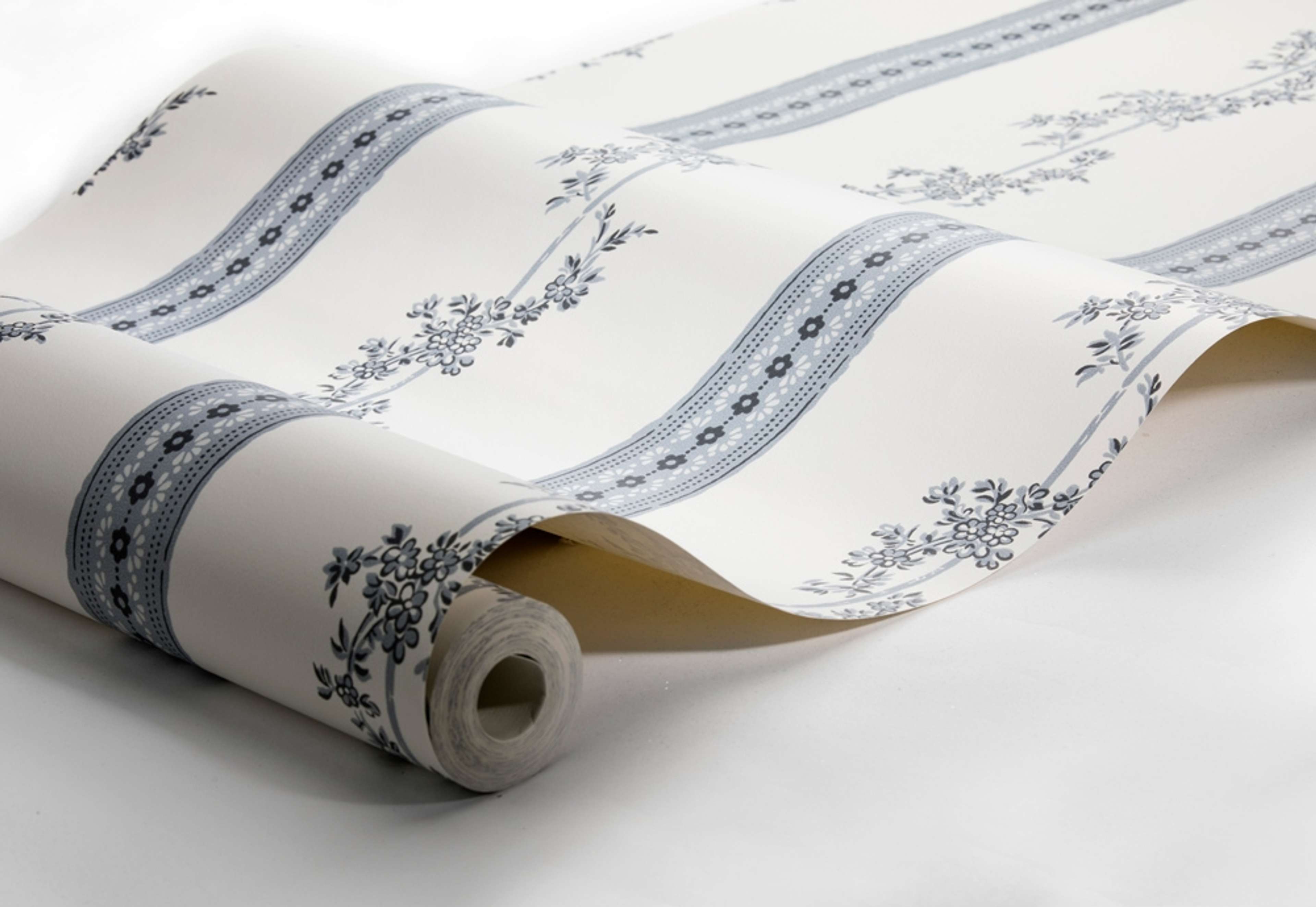Drottningholm tapet från Boråstapeter med randigt, blommigt mönster i vit och blå. Från kollektionen anno. Nonwoven-material med rak passning. Passar i sovrum och matsal.