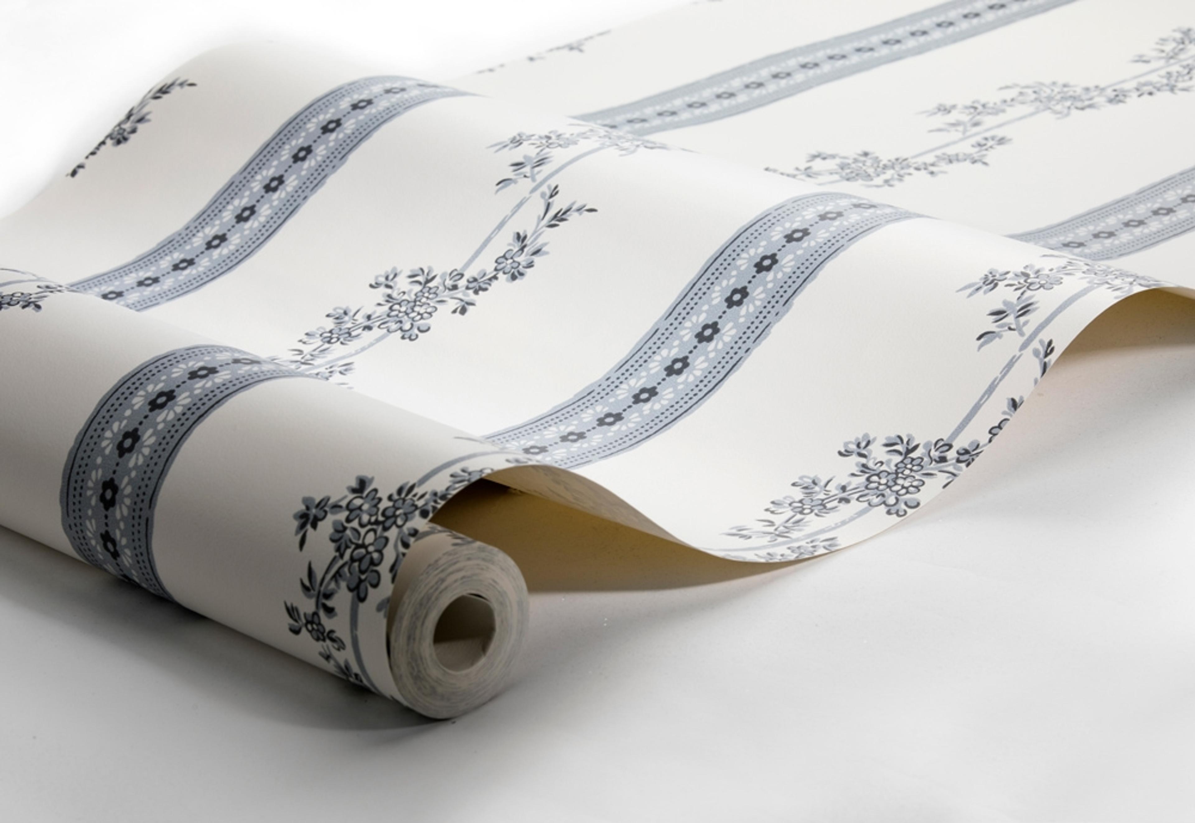 Drottningholm tapet från Boråstapeter med randigt, blommigt mönster i vit och blå. Från kollektionen anno. Nonwoven-material med rak passning. Passar i sovrum och matsal.