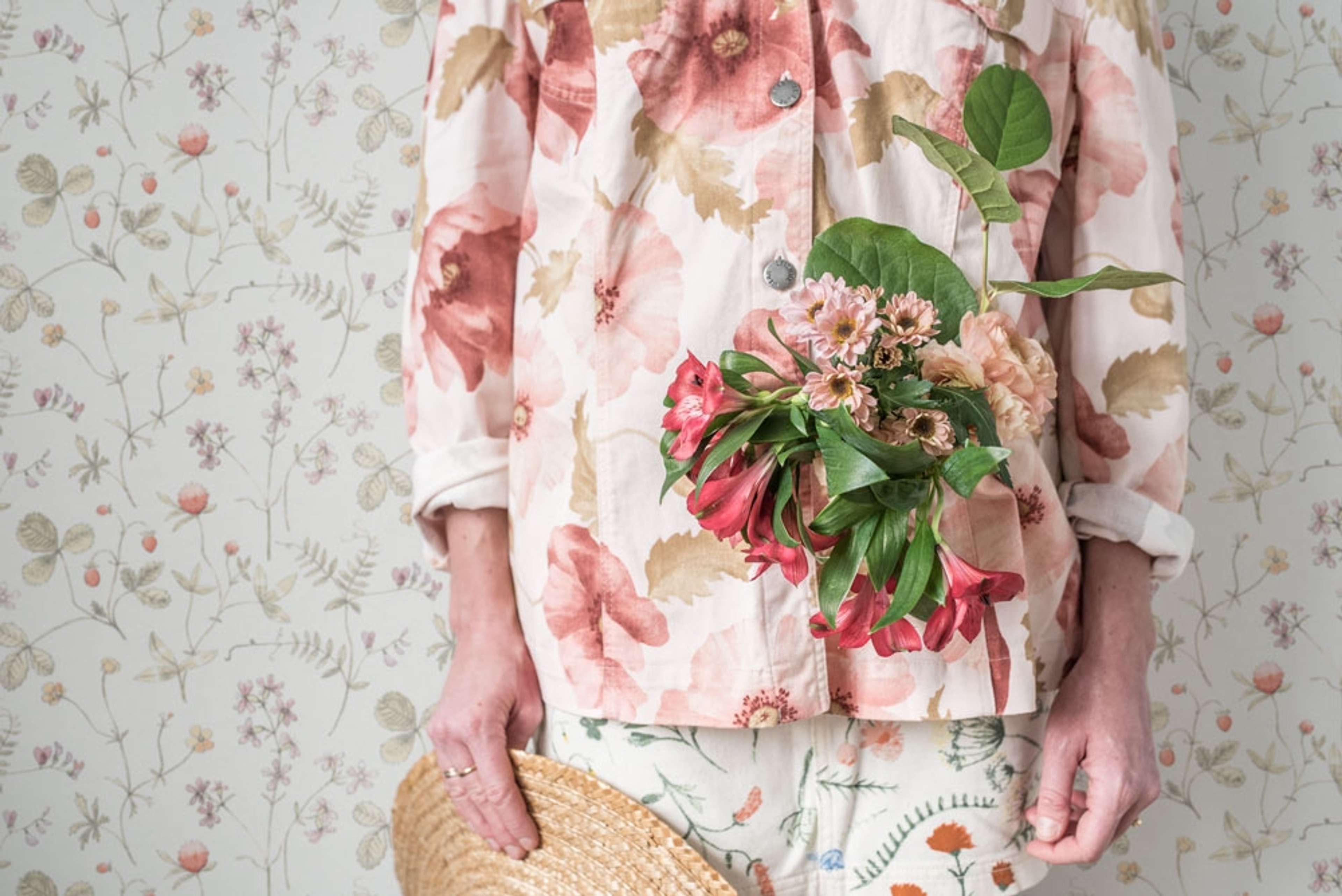 Julia ängsblommor i rosa, rött och orange tapet från Midbec med blommigt mönster i rosa. Från kollektionen Morgongåva. Nonwoven-material med rak passning.