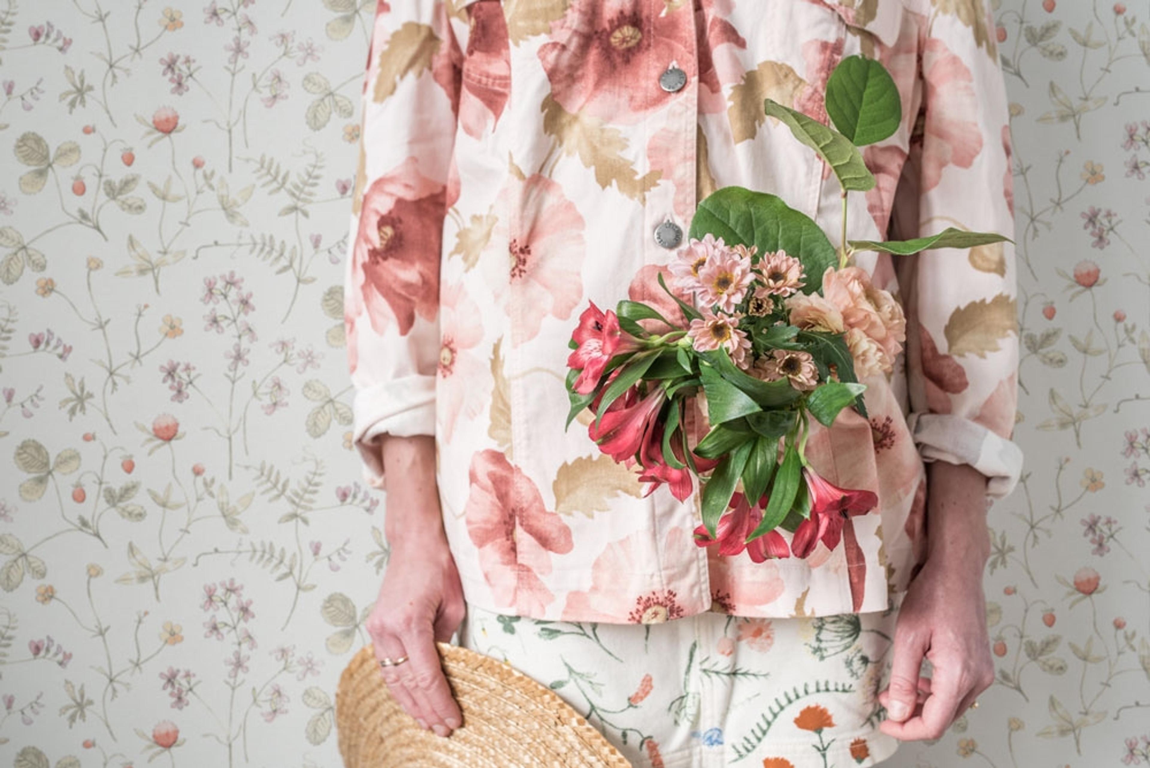Julia ängsblommor i rosa, rött och orange tapet från Midbec med blommigt mönster i rosa. Från kollektionen Morgongåva. Nonwoven-material med rak passning.