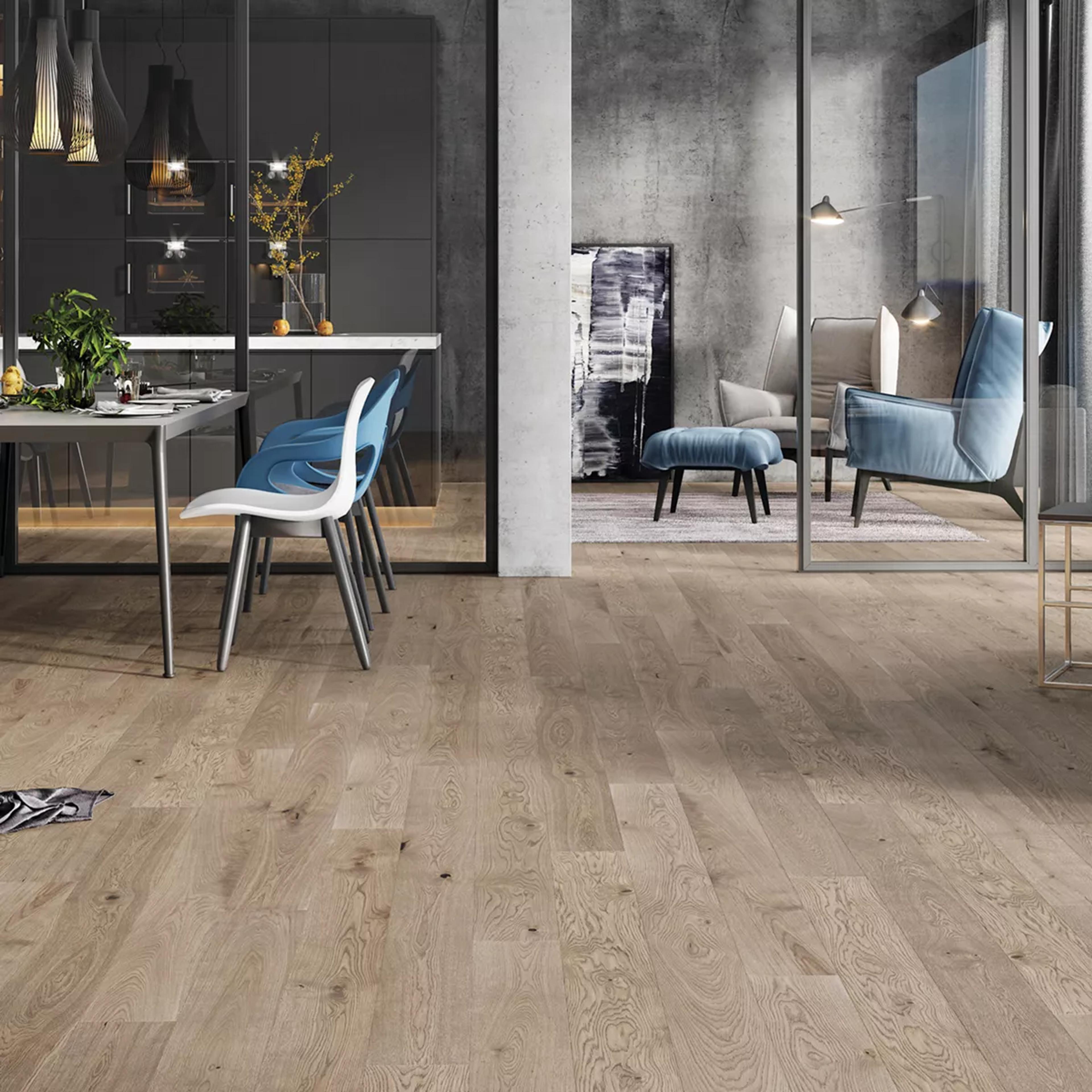 Modern open-plan dining and living area with light wood flooring and concrete walls.