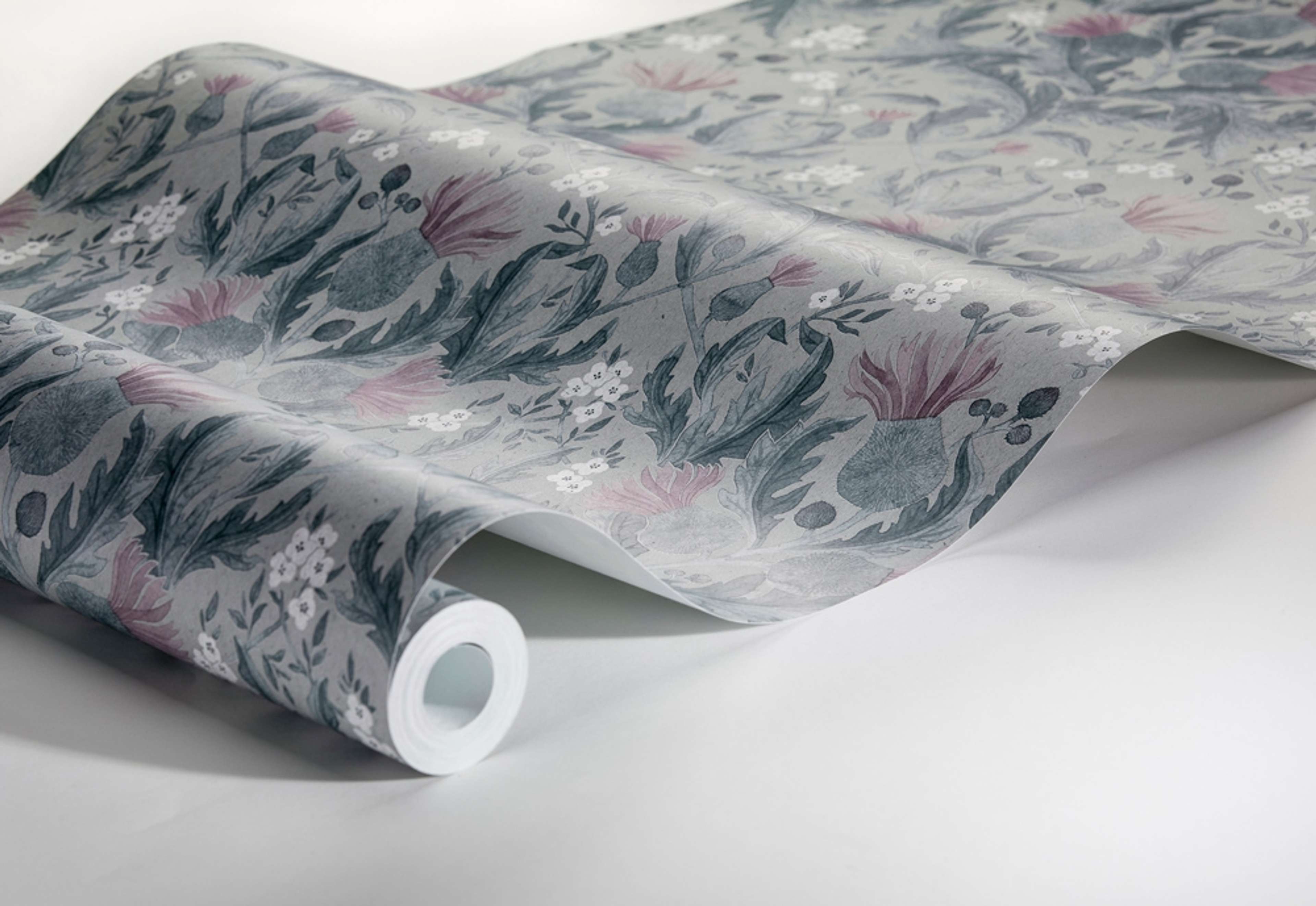 Thistle, blågrön tapet från Boråstapeter med blommigt mönster i grå och blå. Från kollektionen In Bloom. Nonwoven-material med rak passning. Country, city-stil. Passar i vardagsrum, sovrum och hall.