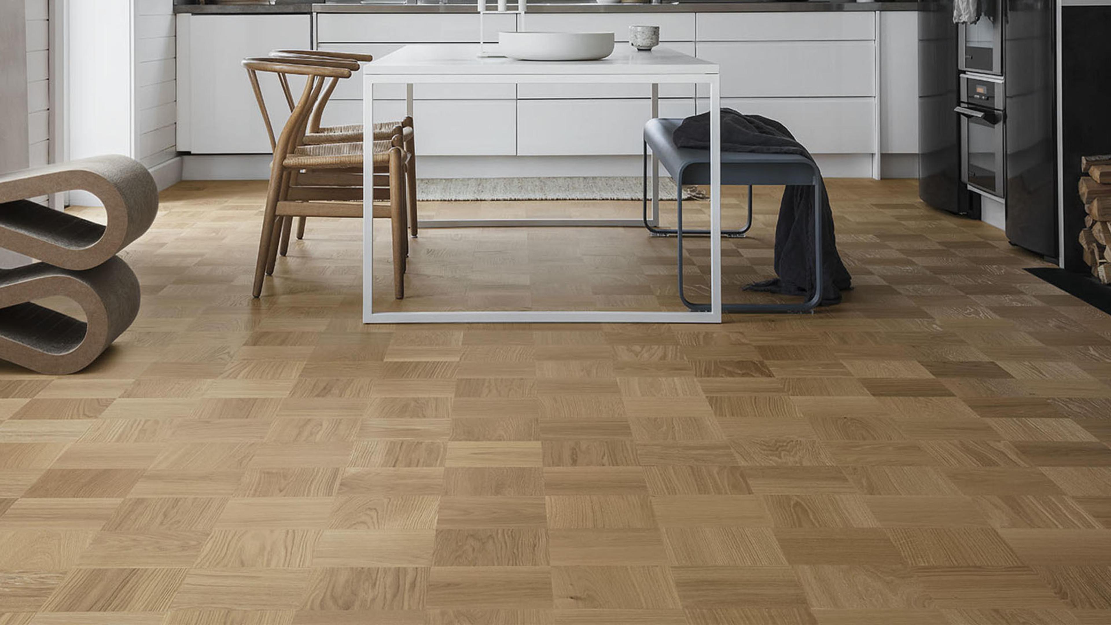 Modern kitchen and dining area with light brown parquet wood flooring.