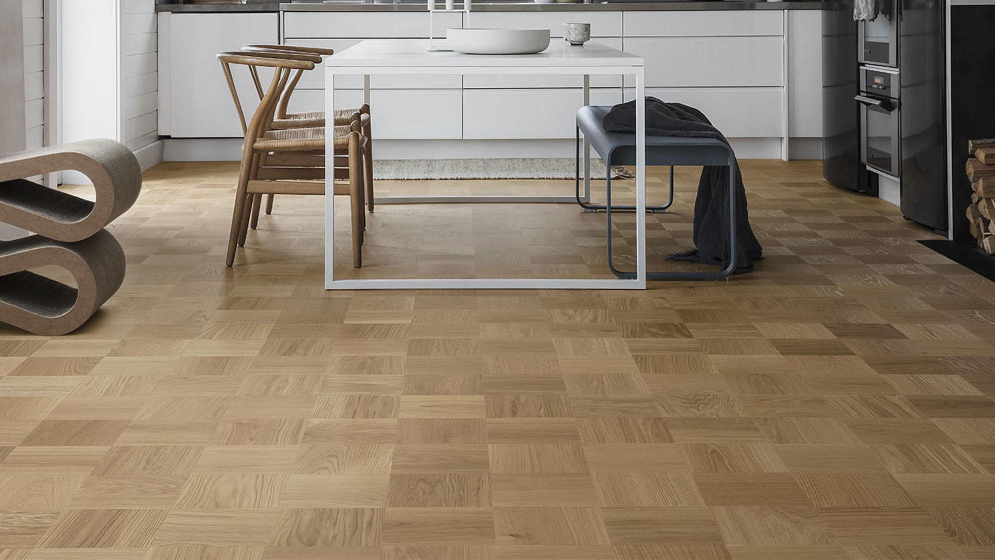 Modern kitchen and dining area with light brown parquet wood flooring.