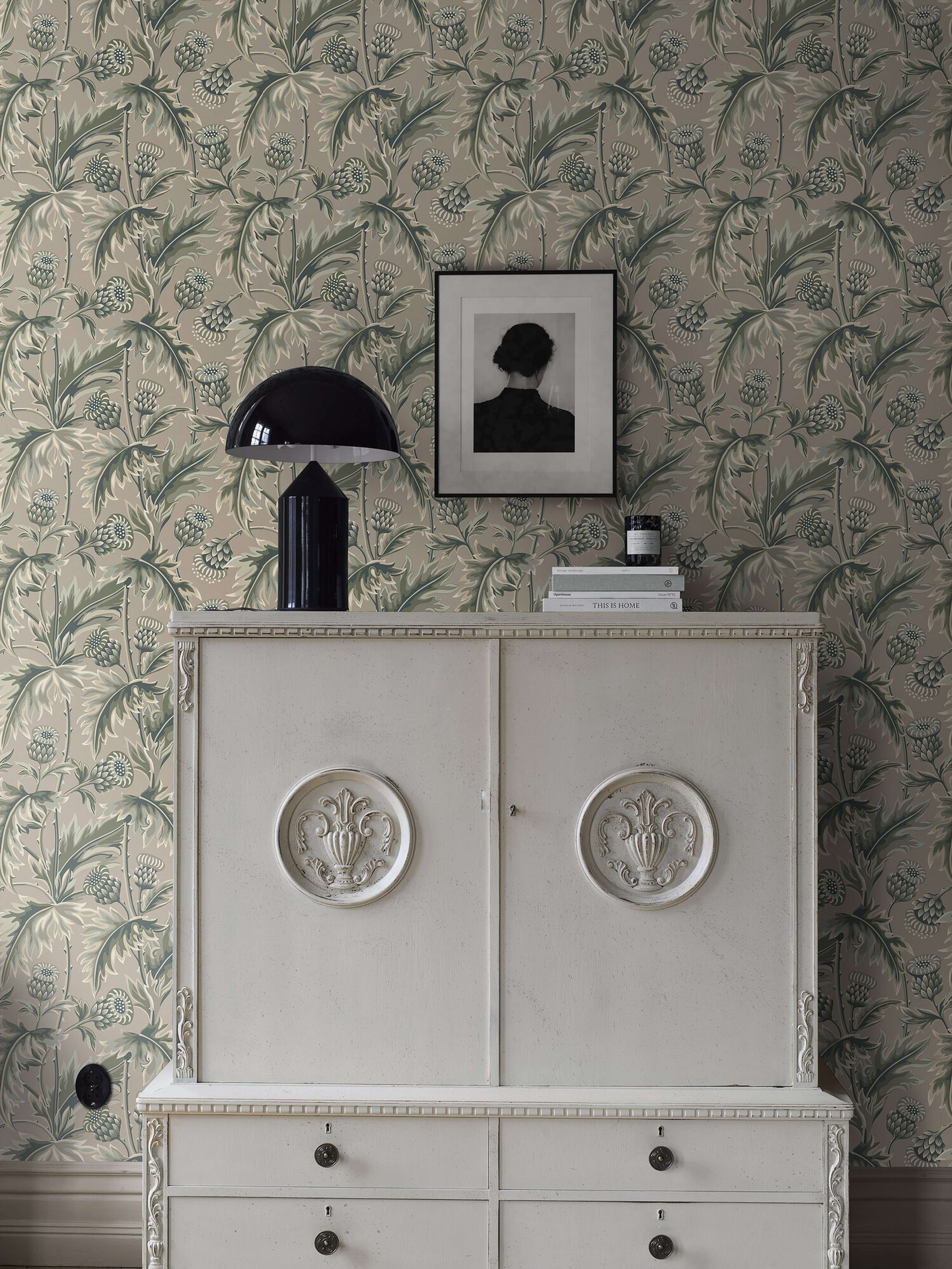 Treasured Thistle tapet i grönt och varmt beige tapet med botaniskt, blommigt mönster i grön. Från kollektionen Treasured. Nonwoven-material med förskjuten passning. Passar i kök, hall och arbetsrum.