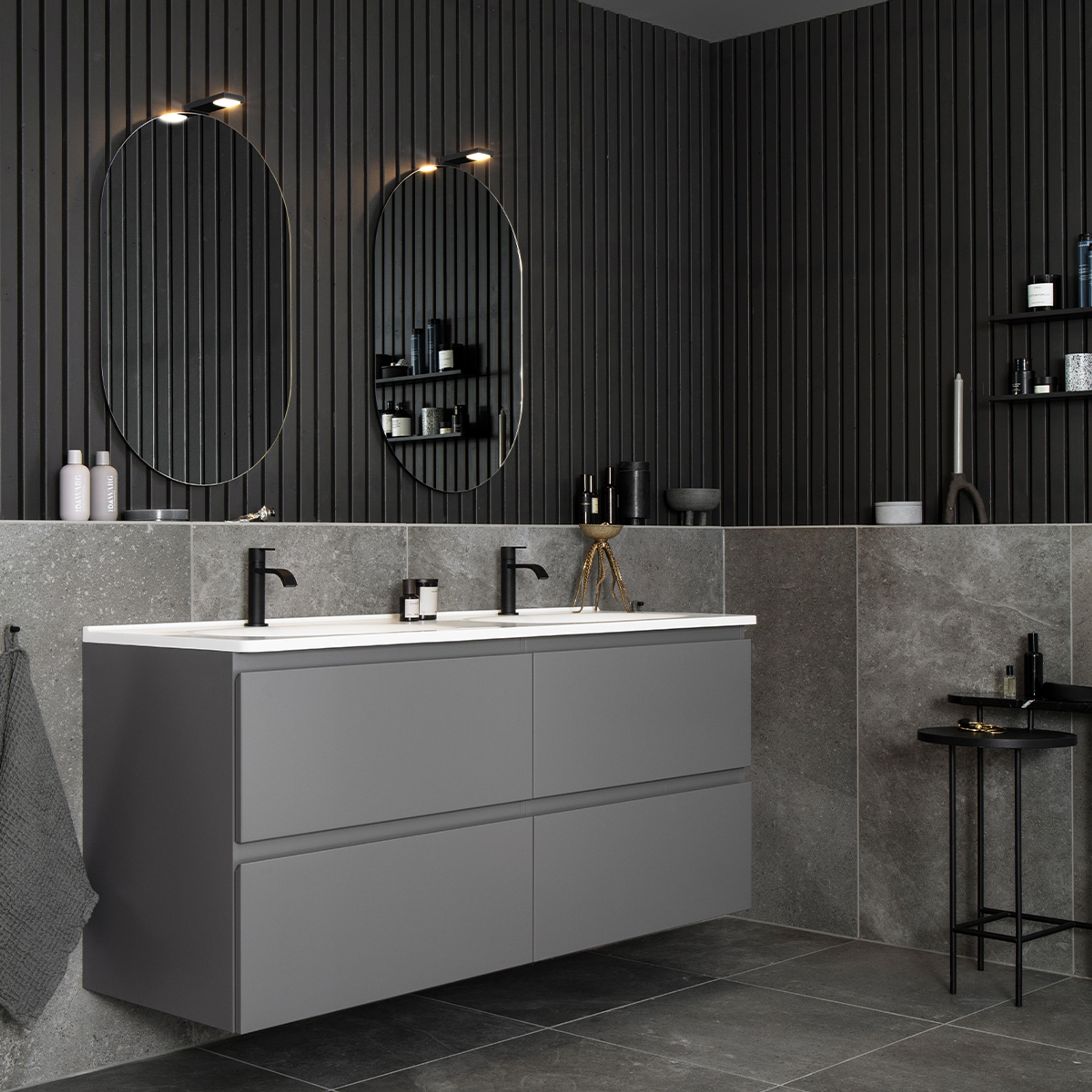 A modern bathroom with a dark gray floating double vanity, two black faucets, oval mirrors, and dark slatted walls.