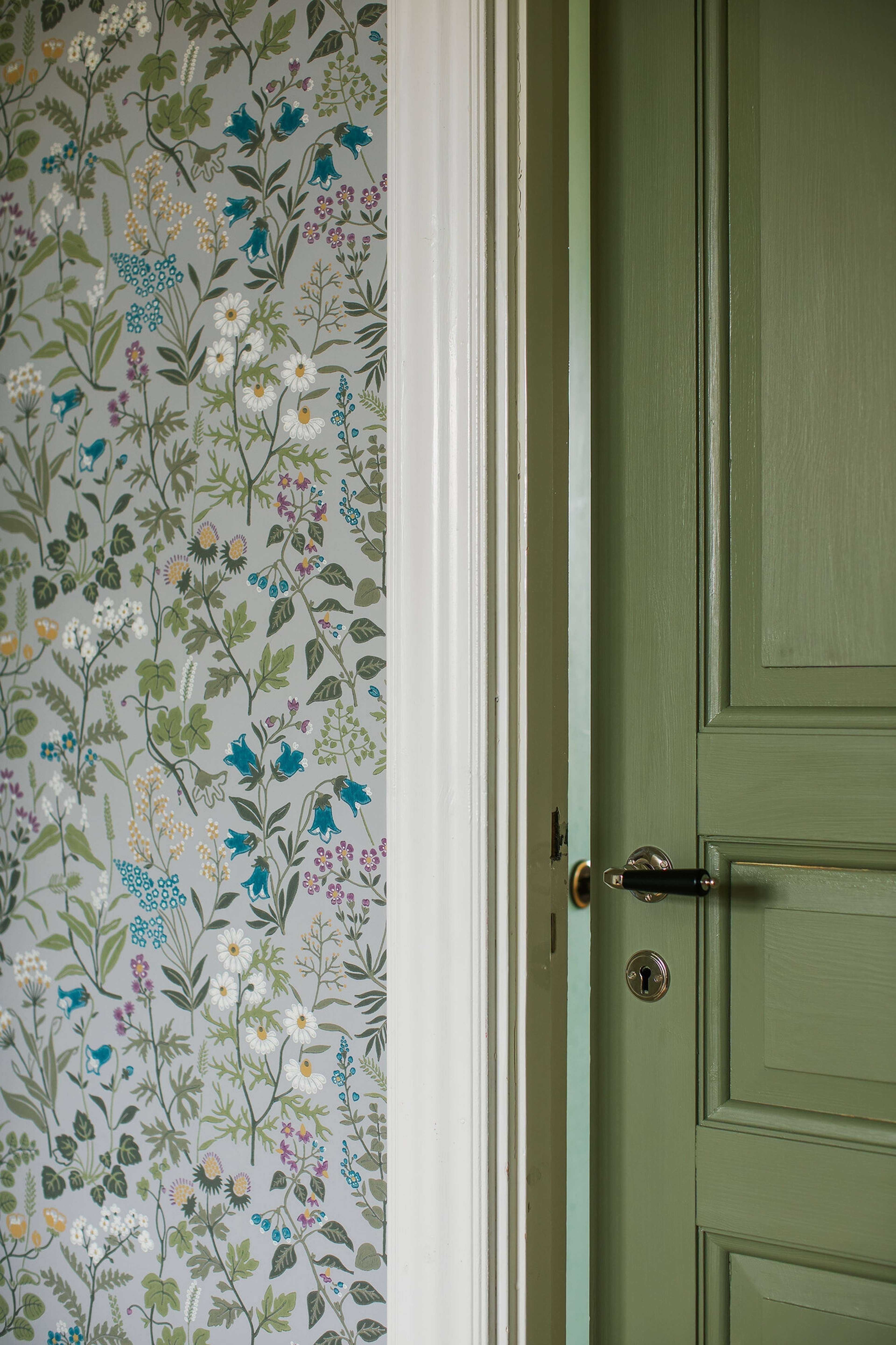 Flora tapet med blommigt mönster i grå. Från kollektionen Alla Tiders Hus. Nonwoven-material med förskjuten passning. Passar i vardagsrum, matsal och kök.