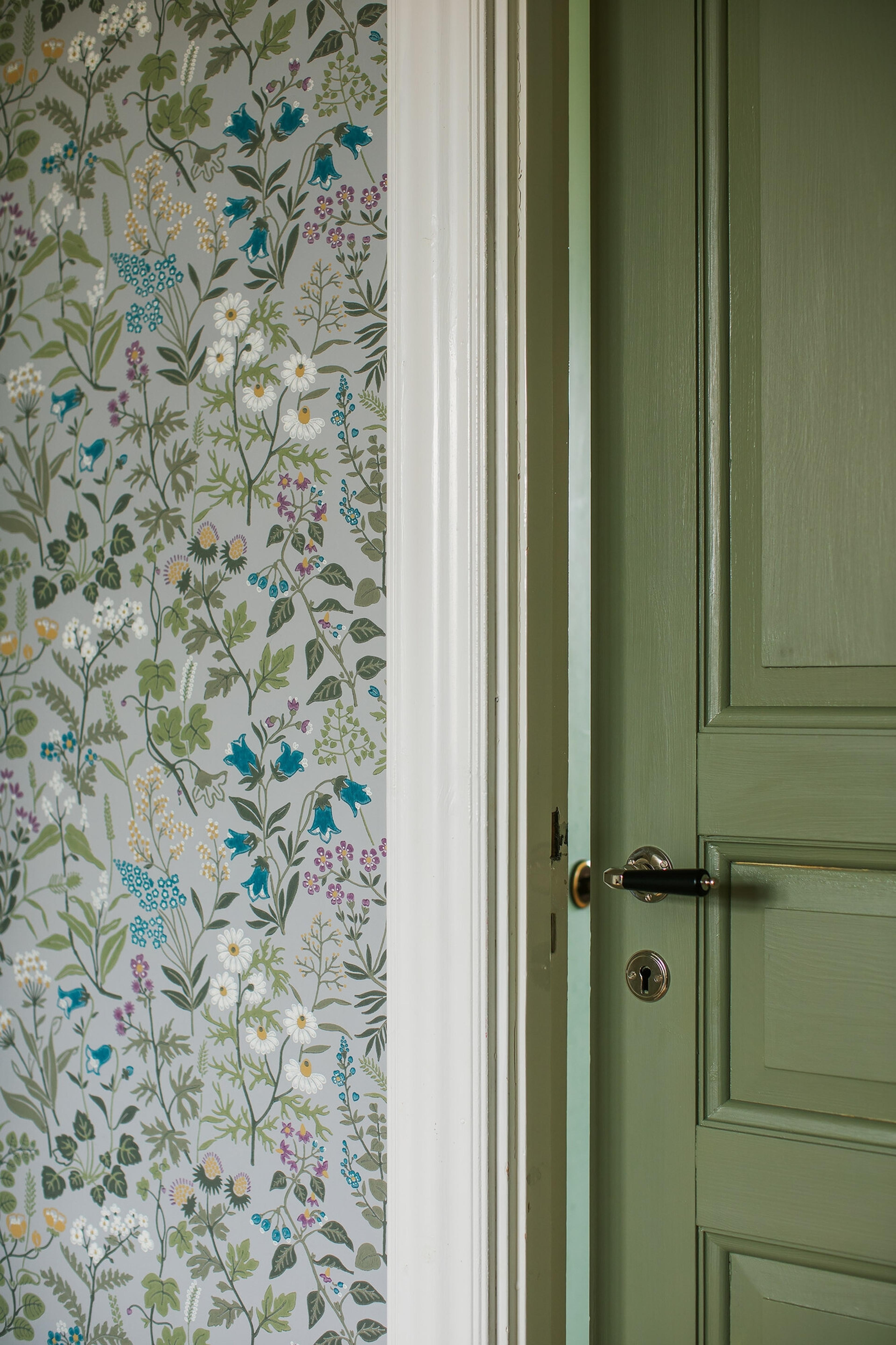 Flora tapet med blommigt mönster i grå. Från kollektionen Alla Tiders Hus. Nonwoven-material med förskjuten passning. Passar i vardagsrum, matsal och kök.