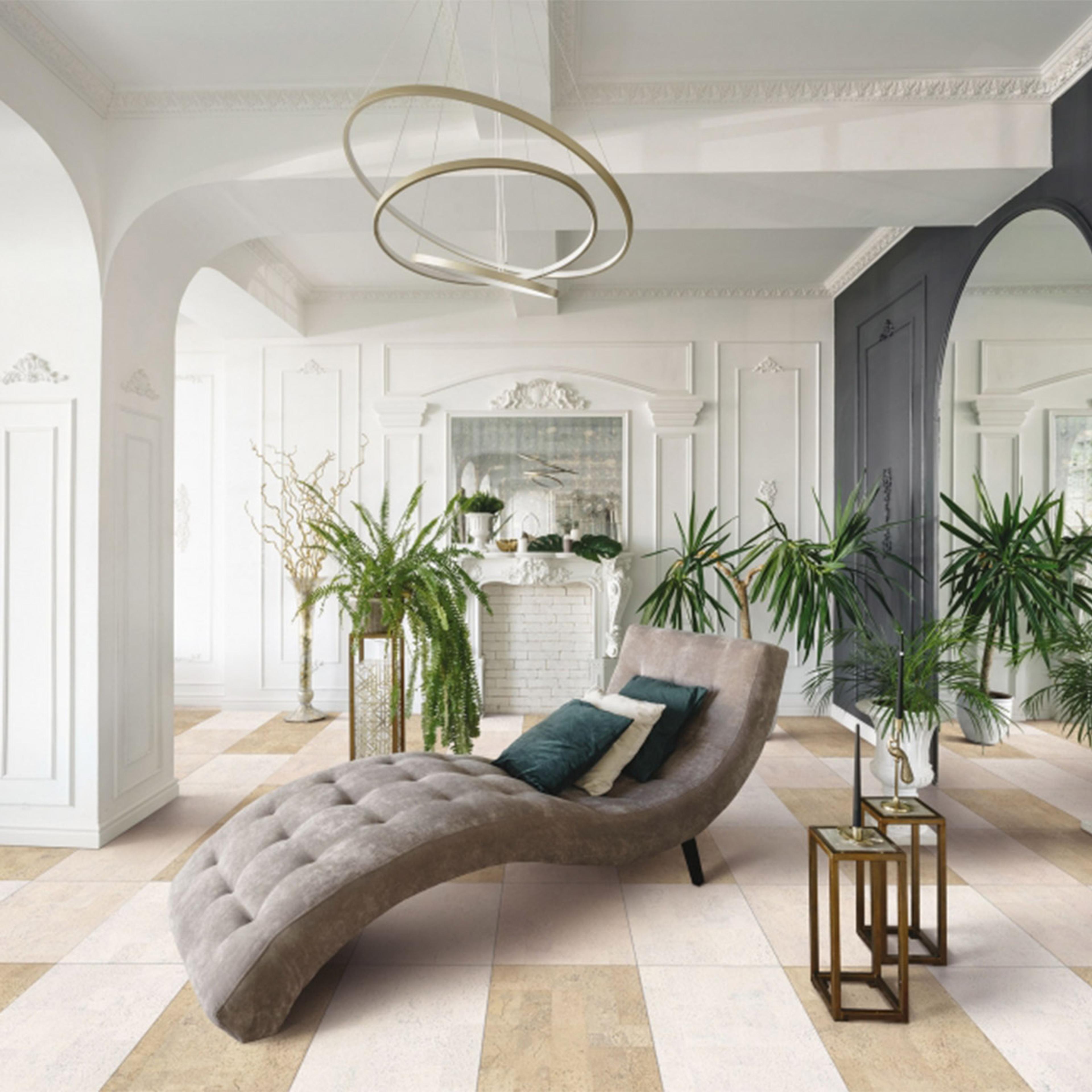 A stylish room with a gray chaise lounge, many plants, a modern chandelier, and a beige and cream checkered floor.